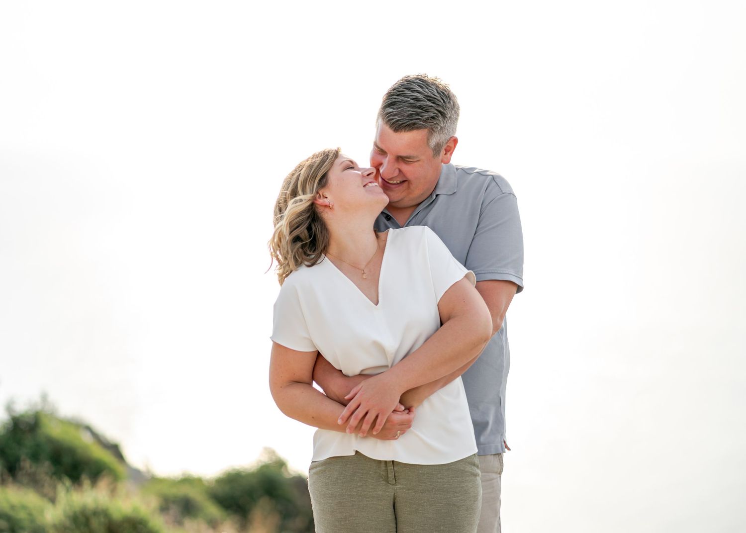 Loving couple embraces on white background during outdoor photoshoot. Fotograf Rhodos