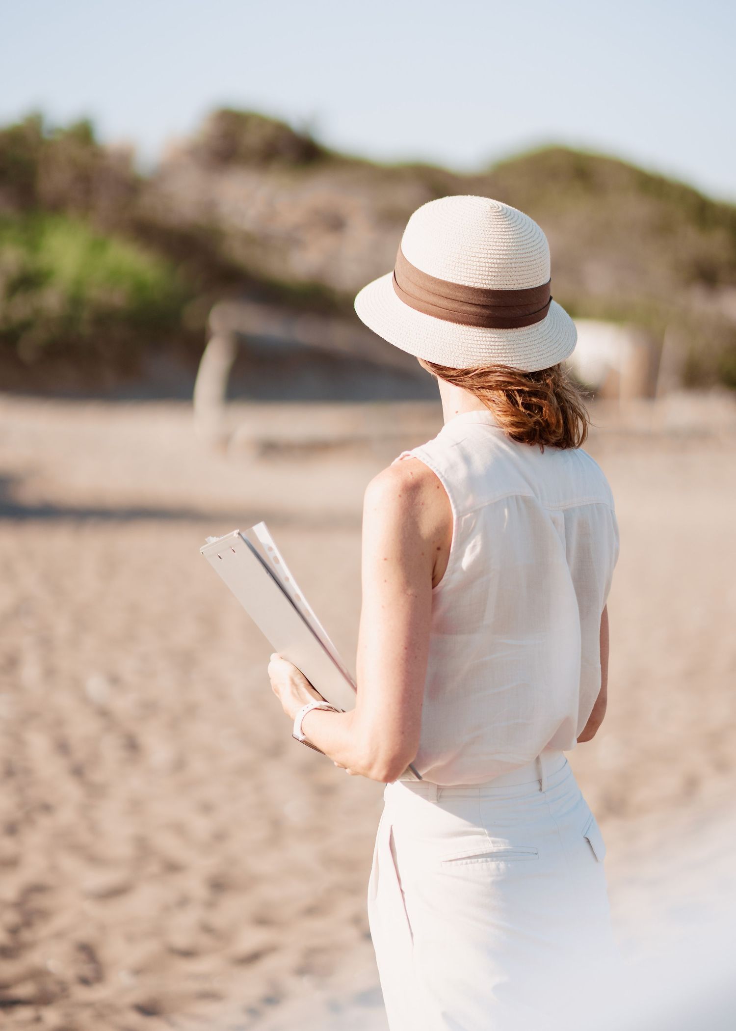 Person in a white dress and sun hat walking along the beach during a wedding ceremony.heiraten am Strand - Hochzeitsfotograf Rhodos Tina Luc