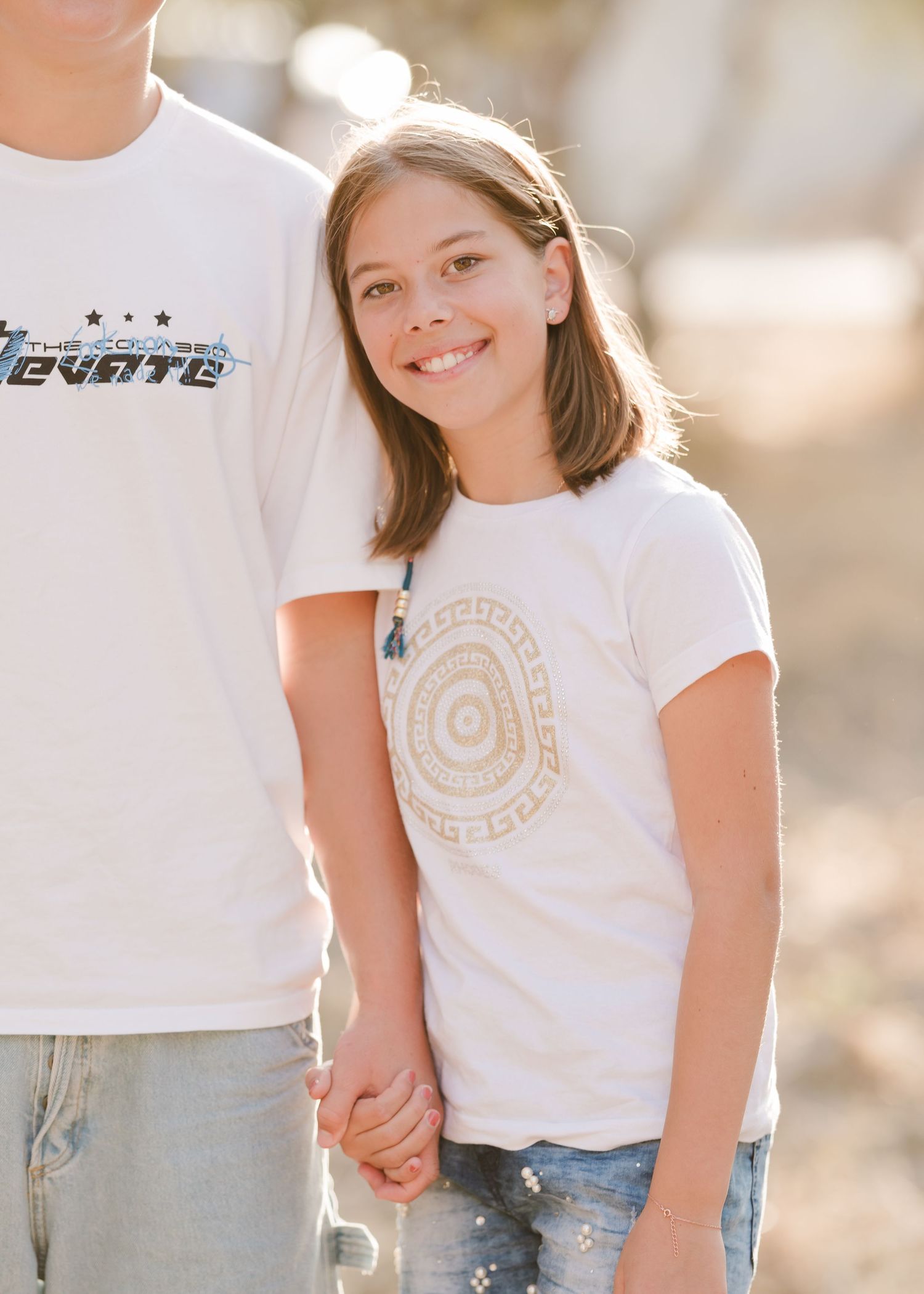 Child wearing white t-shirt with gold design during outdoor family session. Fotograf Rhodos