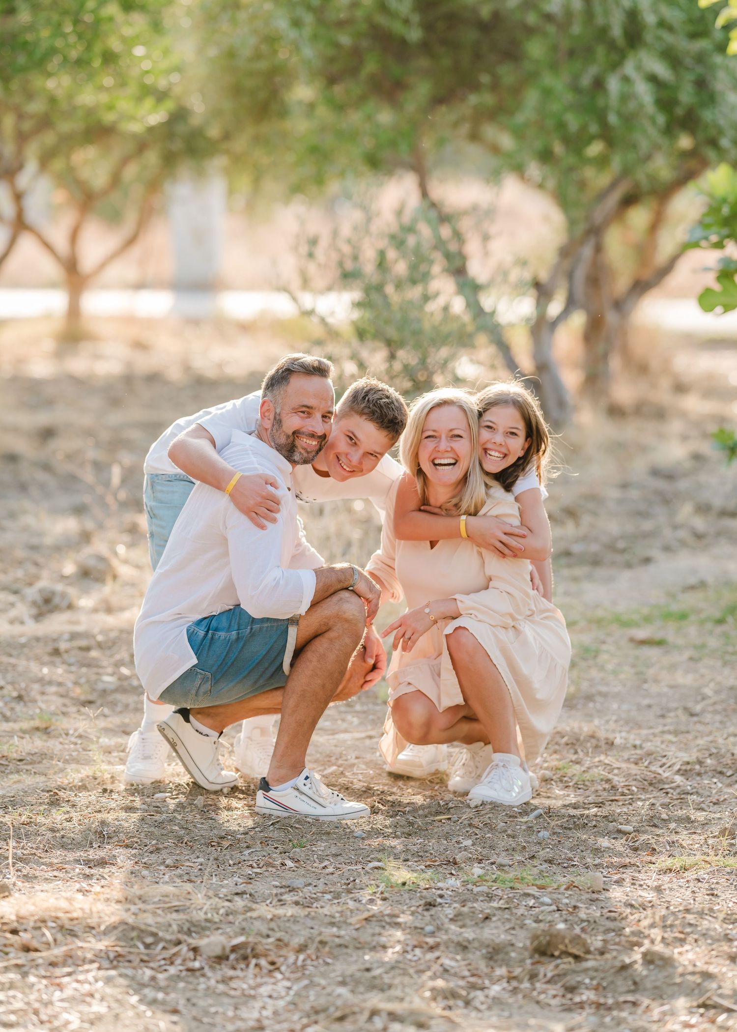Joyful group embrace captured in golden sunlight among olive trees. Fotograf Rhodos
