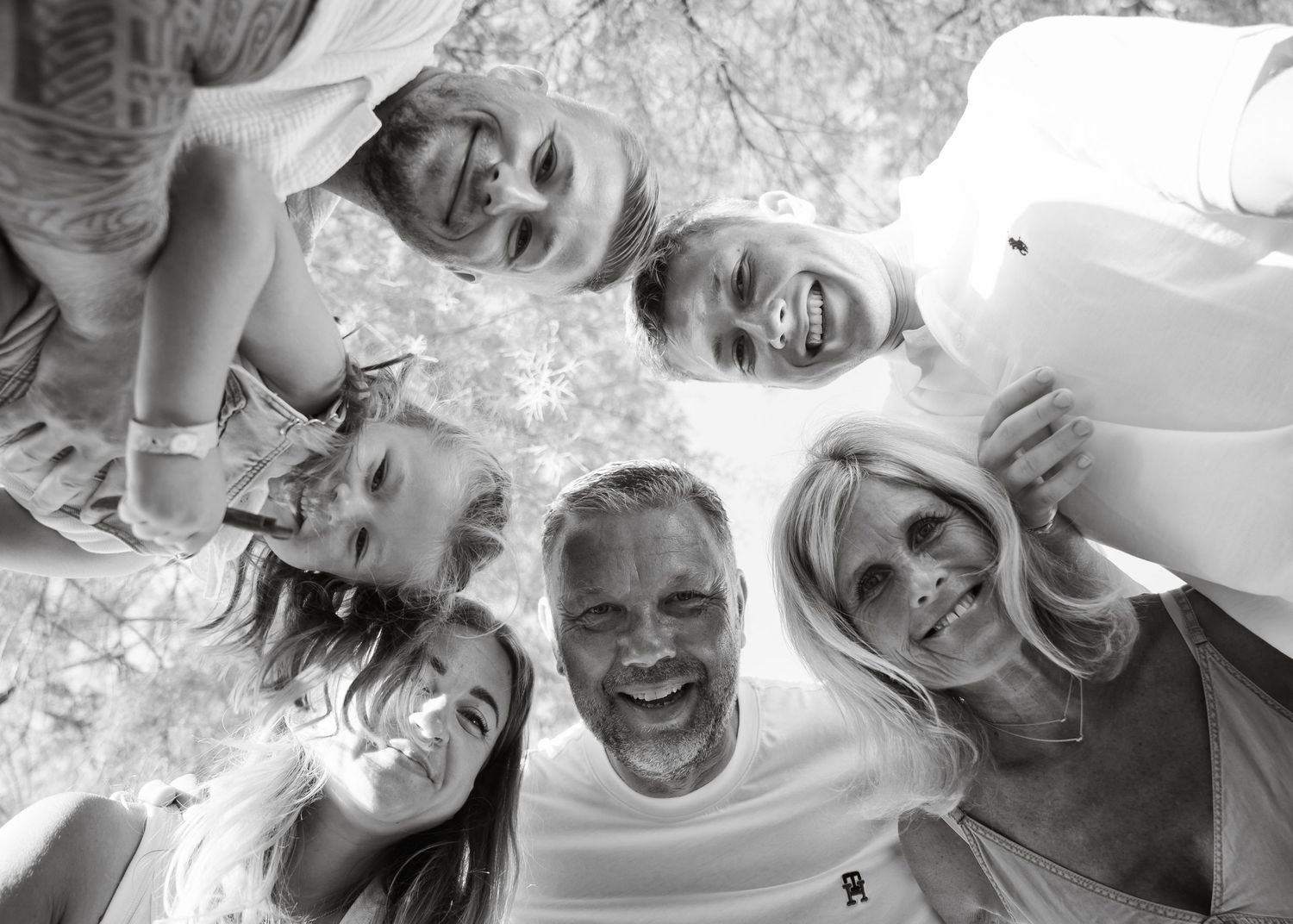 Overhead view of smiling group huddle in black and white photo showing playful expressions and unity. Fotograf Rhodos