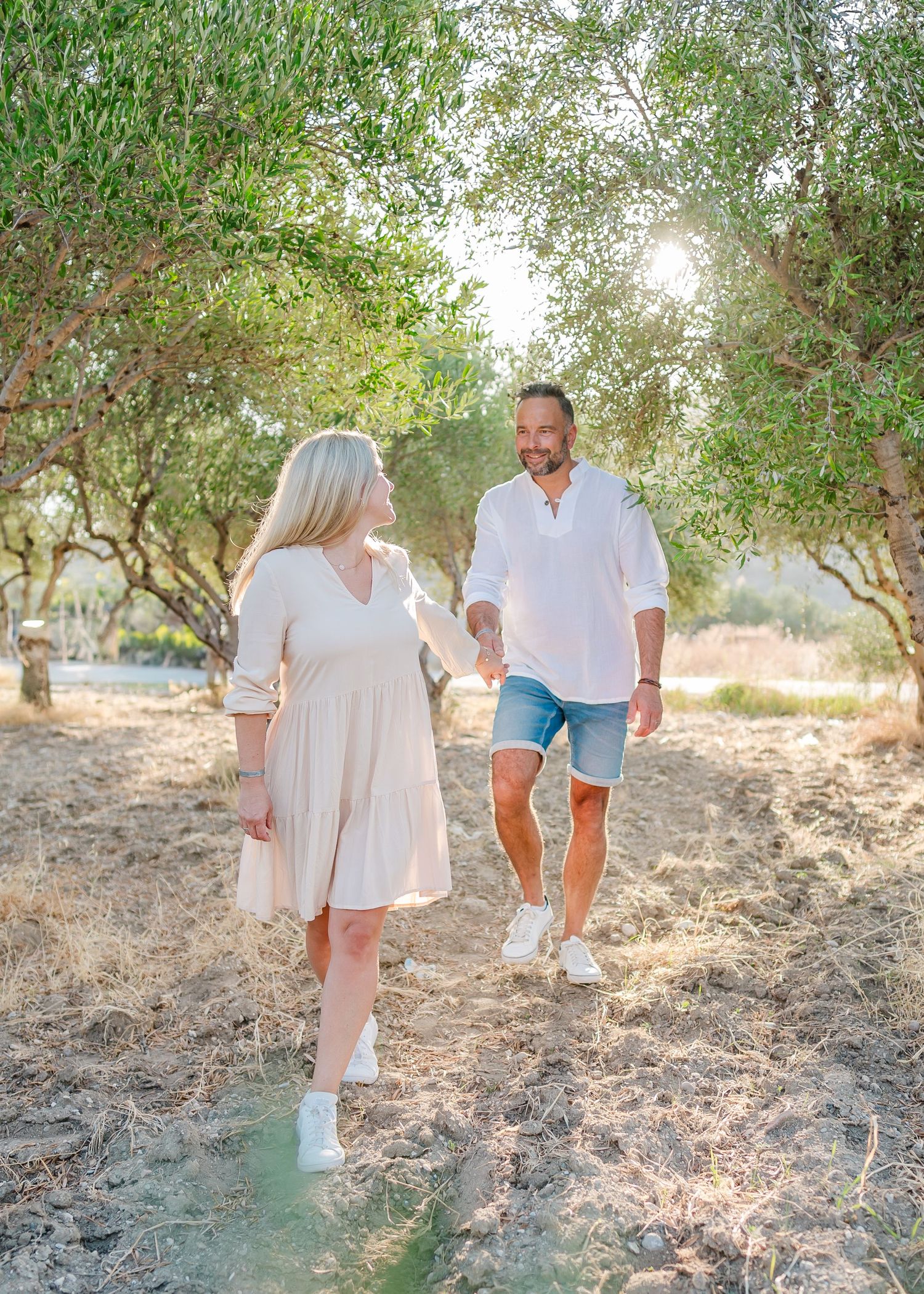 Family walking together through an olive grove in matching casual summer outfits. Fotograf Rhodos