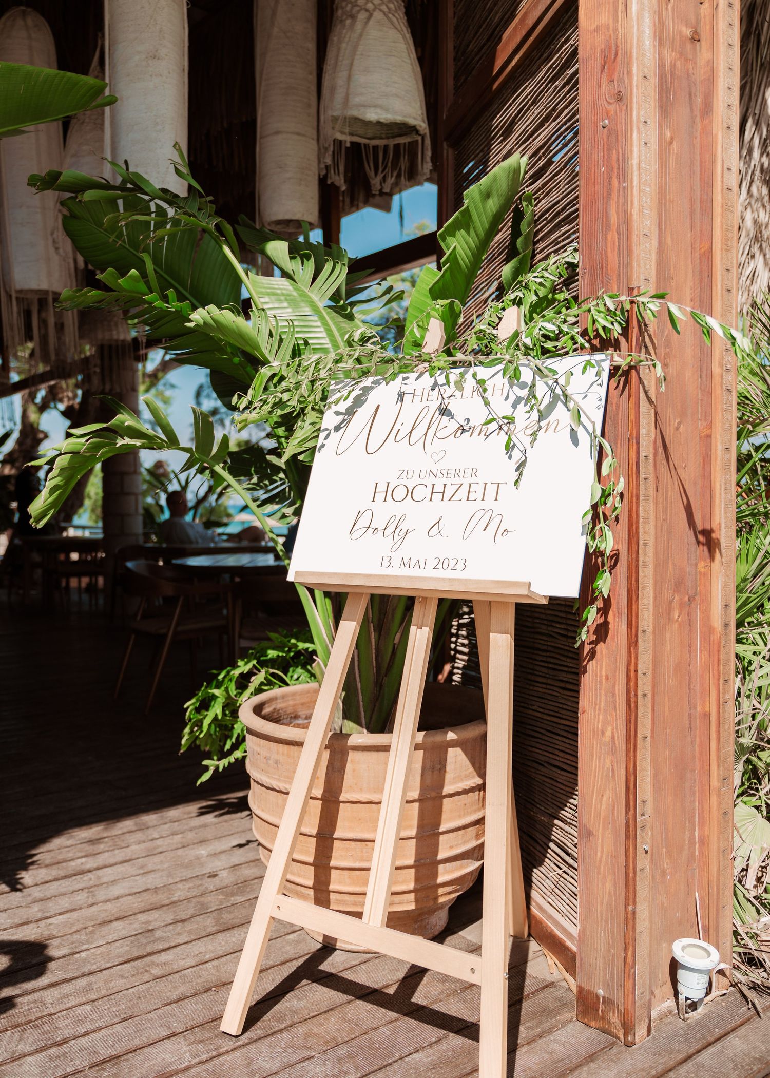 Welcome sign on woohochzeitsfotograf Griechenland - Hochzeitsfotograf Rhodos Tina Lucius 
den easel decorated with tropical greenery.