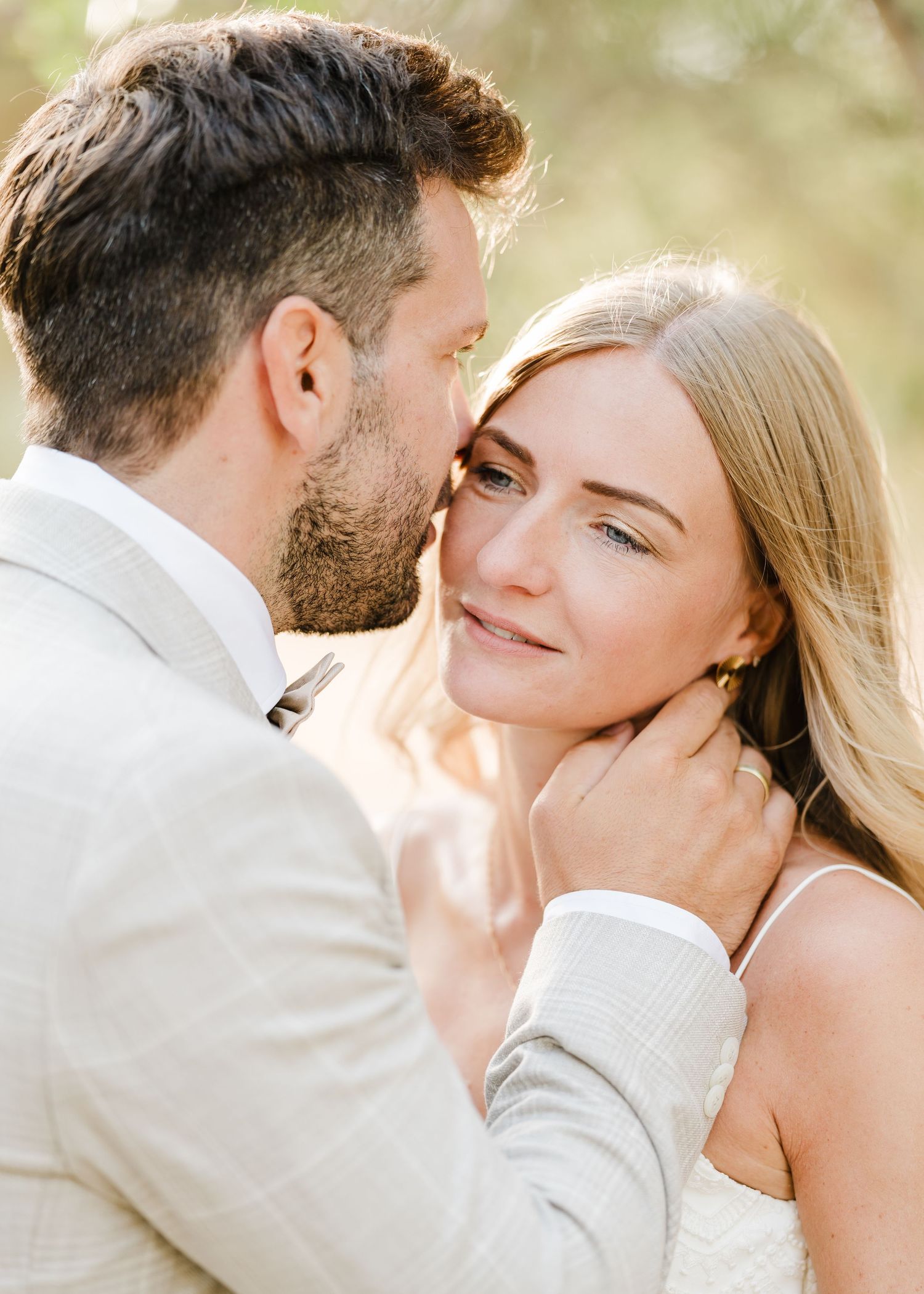 Zärtlicher Moment zwischen Paaren in eleganter Hochzeitskleidung vor sonnenbeschienener Naturkulisse. Hochzeiten Griechenland - Hochzeitsfot