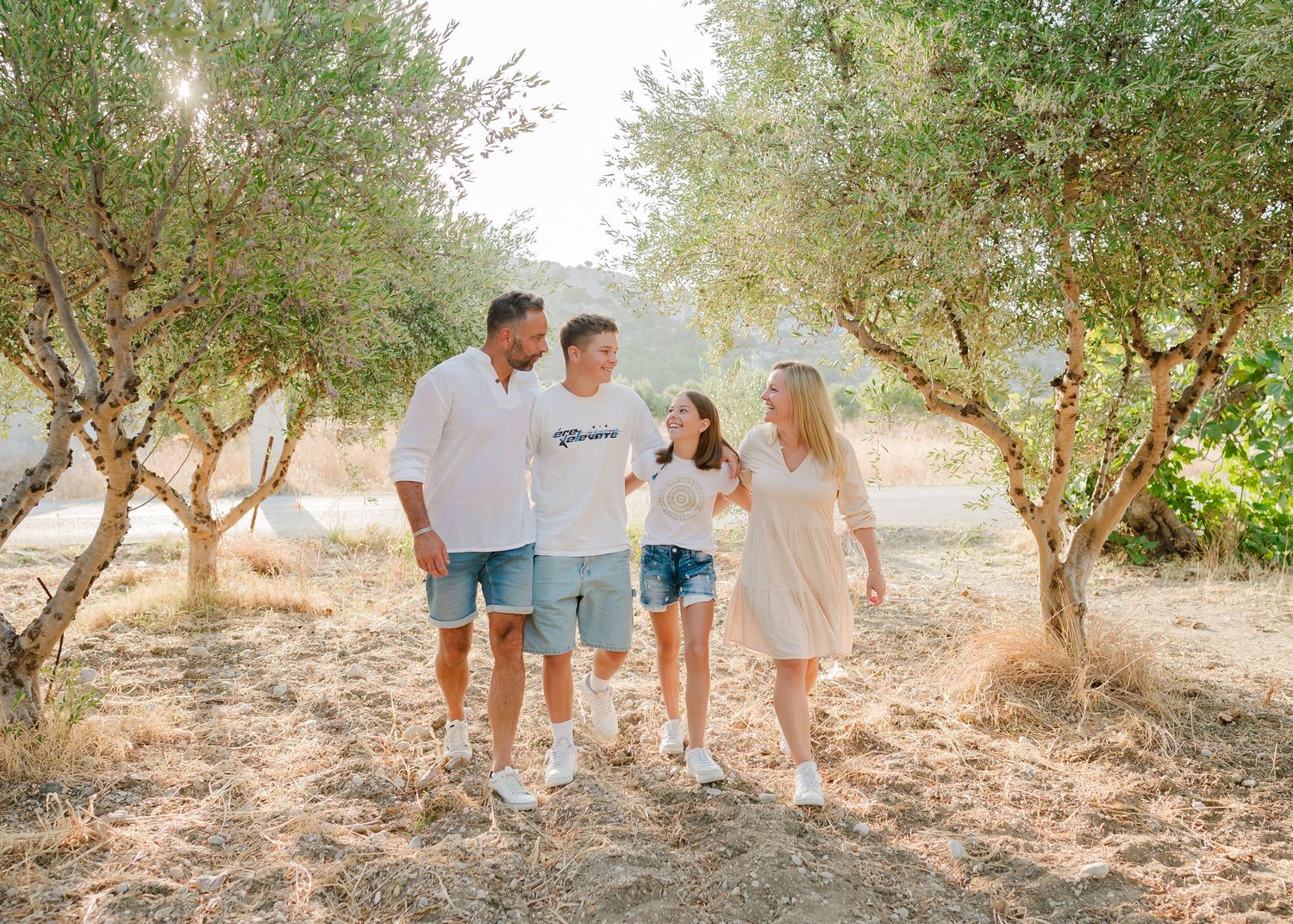 A group walks together through a sun-drenched olive grove on a warm summer day. Fotograf Rhodos