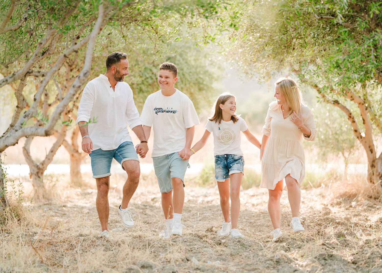 Sun-filled portrait of a group walking together through an olive tree orchard. Fotograf Rhodos