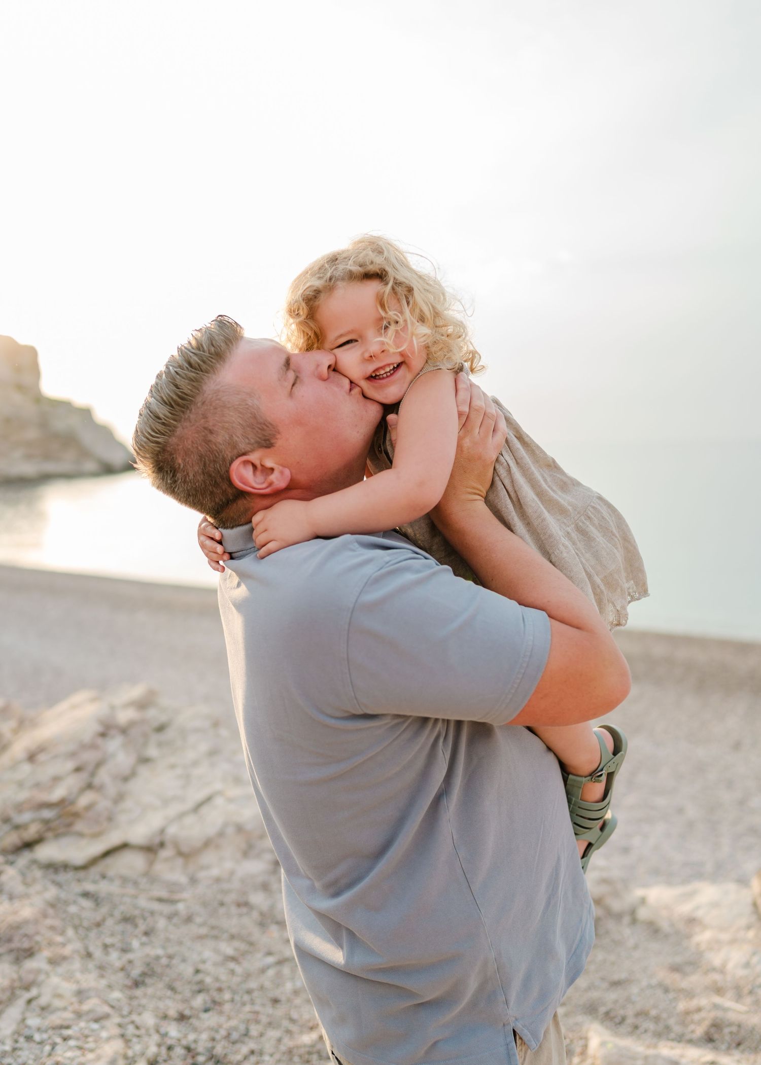 Sweet embrace between parent and child on a rocky beach at sunset. Fotograf Rhodos