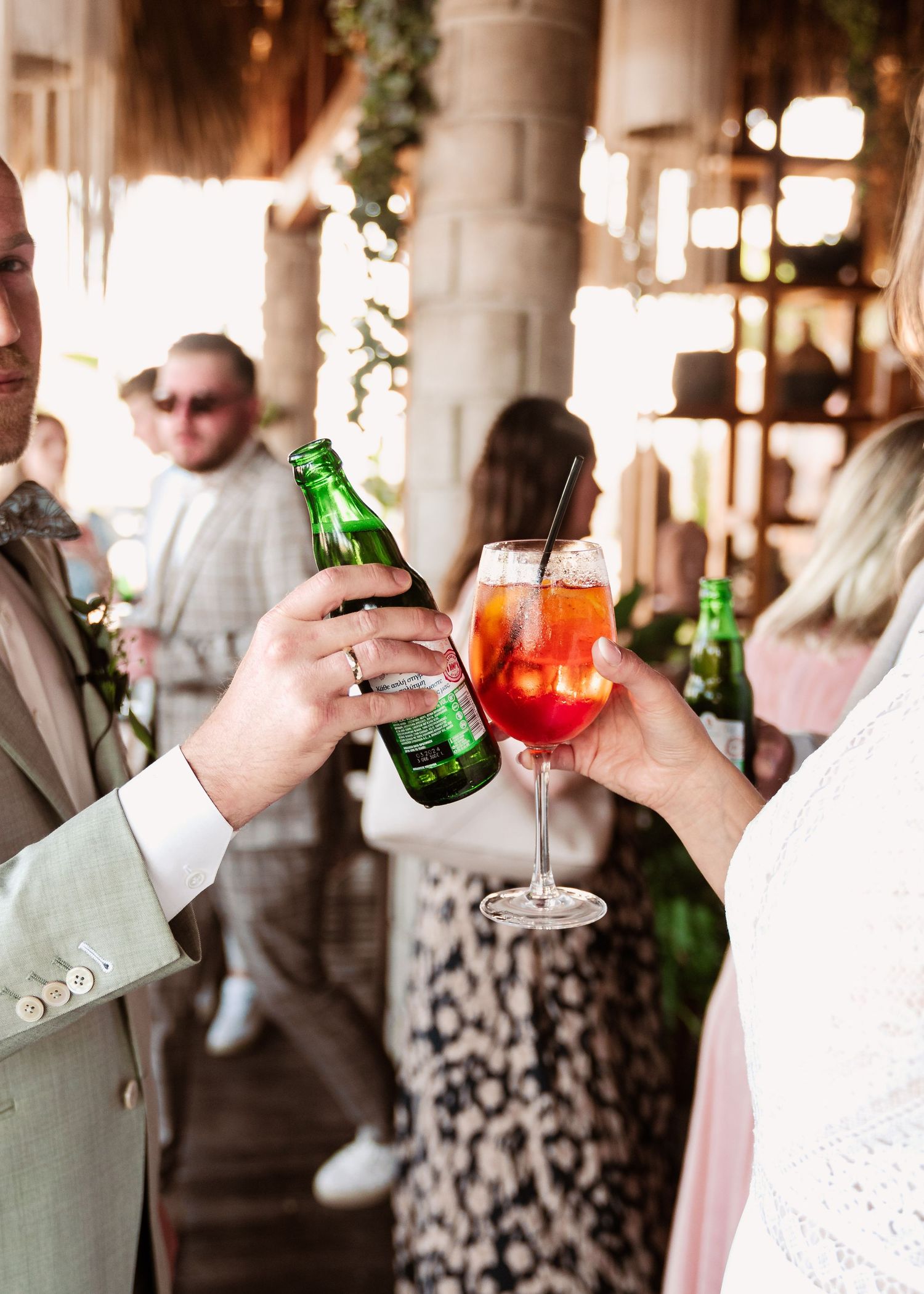 Wedding guests toasting with cocktails and beer bottles in an elegant indoor venue.hochzeitsfotograf Griechenland - Hochzeitsfotograf Rhodos