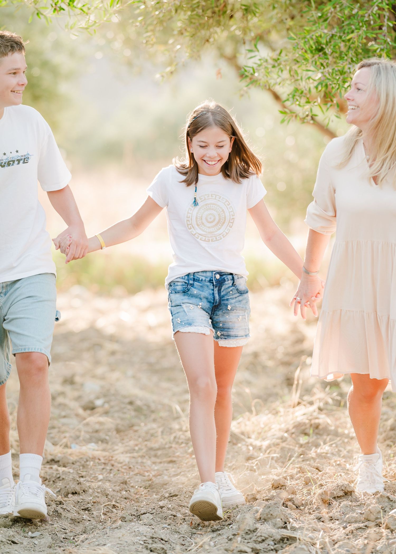 Joyful moment walking hand-in-hand through a sunlit olive grove path. Fotograf Rhodos