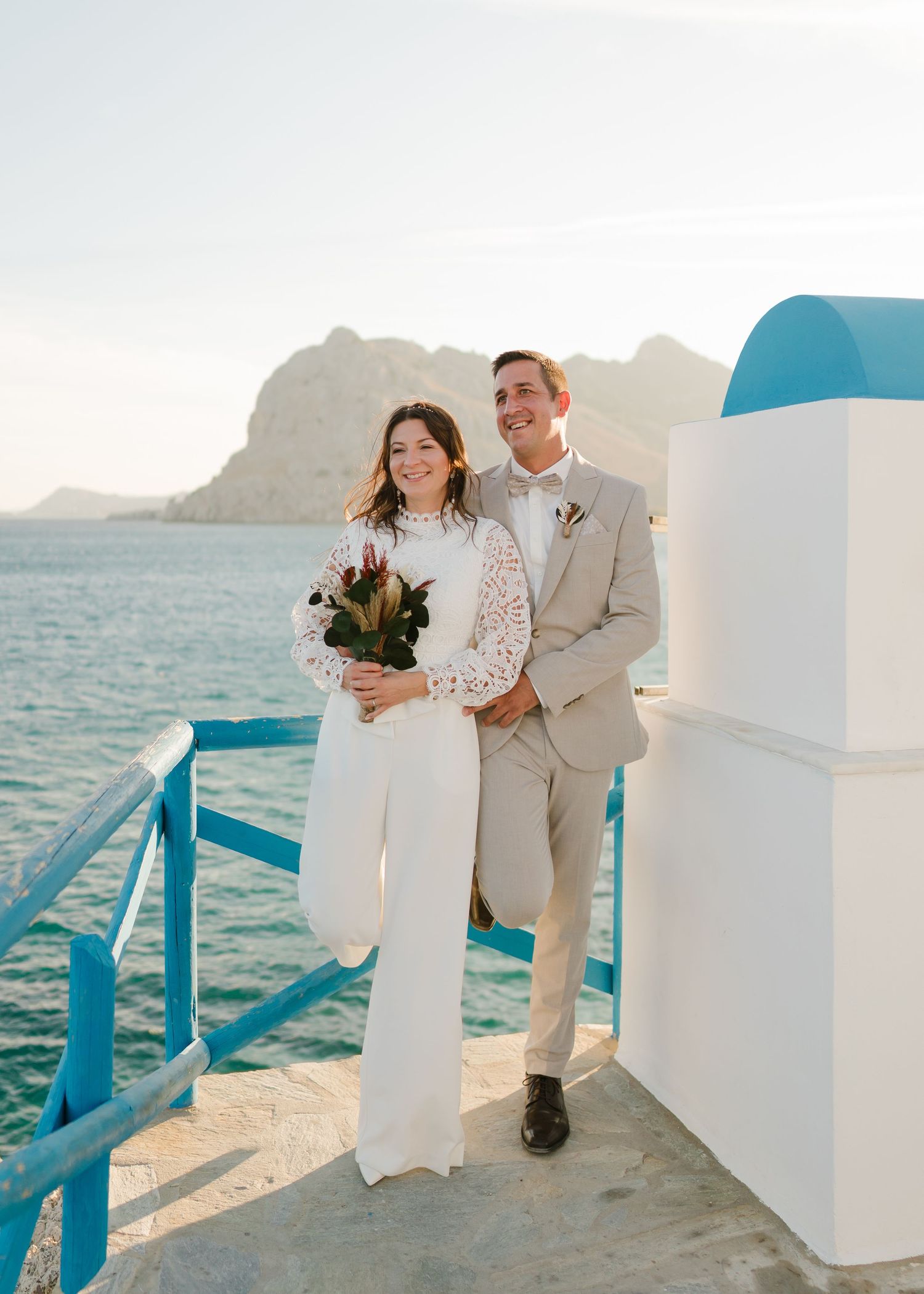 Frischvermählte posieren auf weißer Architektur im Santorin-Stil mit Blick auf die Gewässer des Mittelmeers. heiraten am Strand - Hochzeitsf
