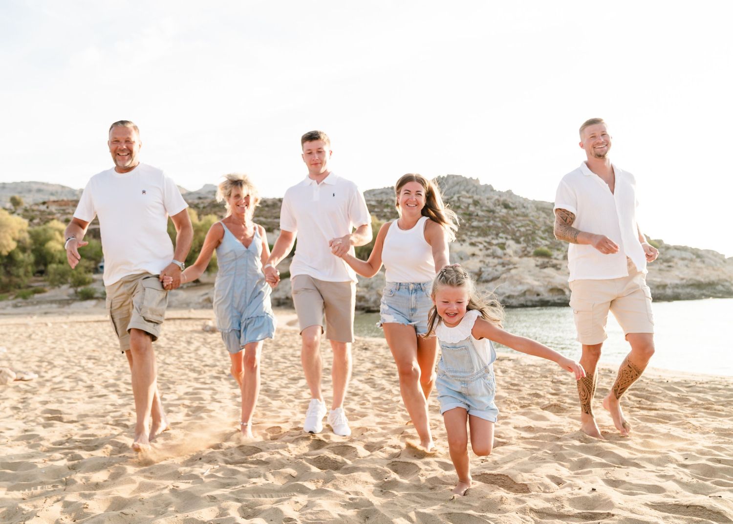 Happy group jumping and playing together on sandy beach at golden hour. Fotograf Rhodos