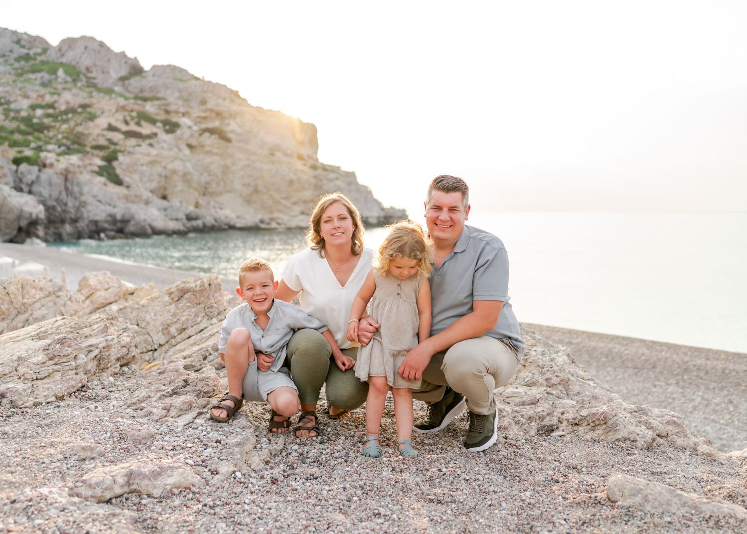 Family portrait session on a rocky beach during golden hour.