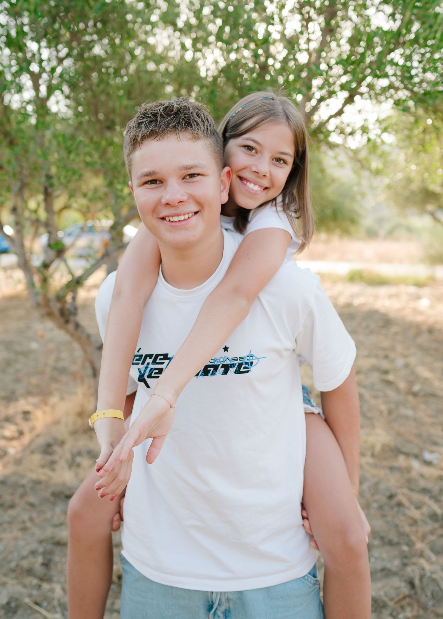 Child smiling and playing outdoors in white t-shirt during family photoshoot. Fotograf Rhodos