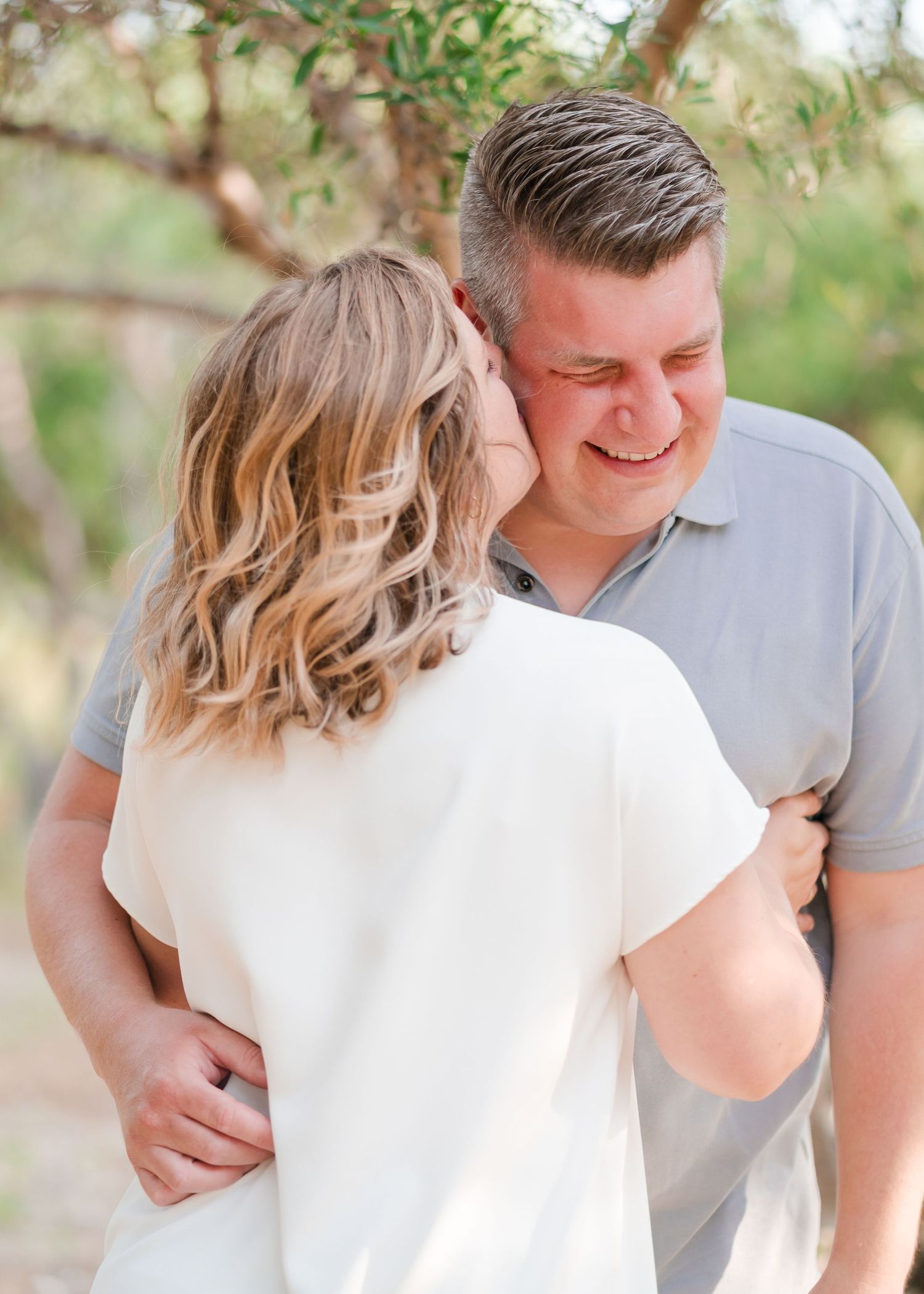 An intimate couple moment captured in warm sunlight under trees. Fotograf Rhodos