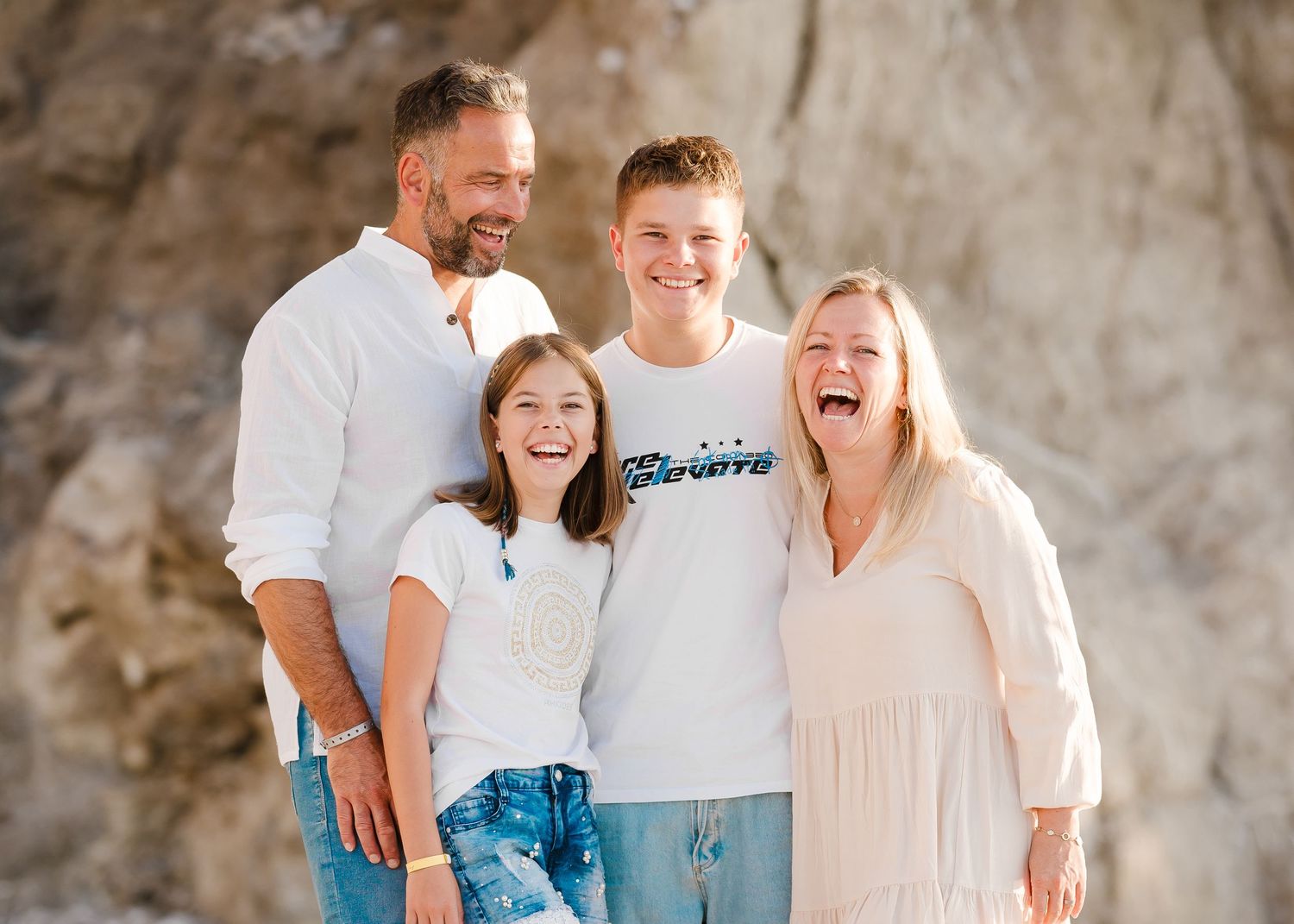 A group shares genuine laughter while posing for a casual photo by rocky coastal cliffs. Fotograf Rhodos