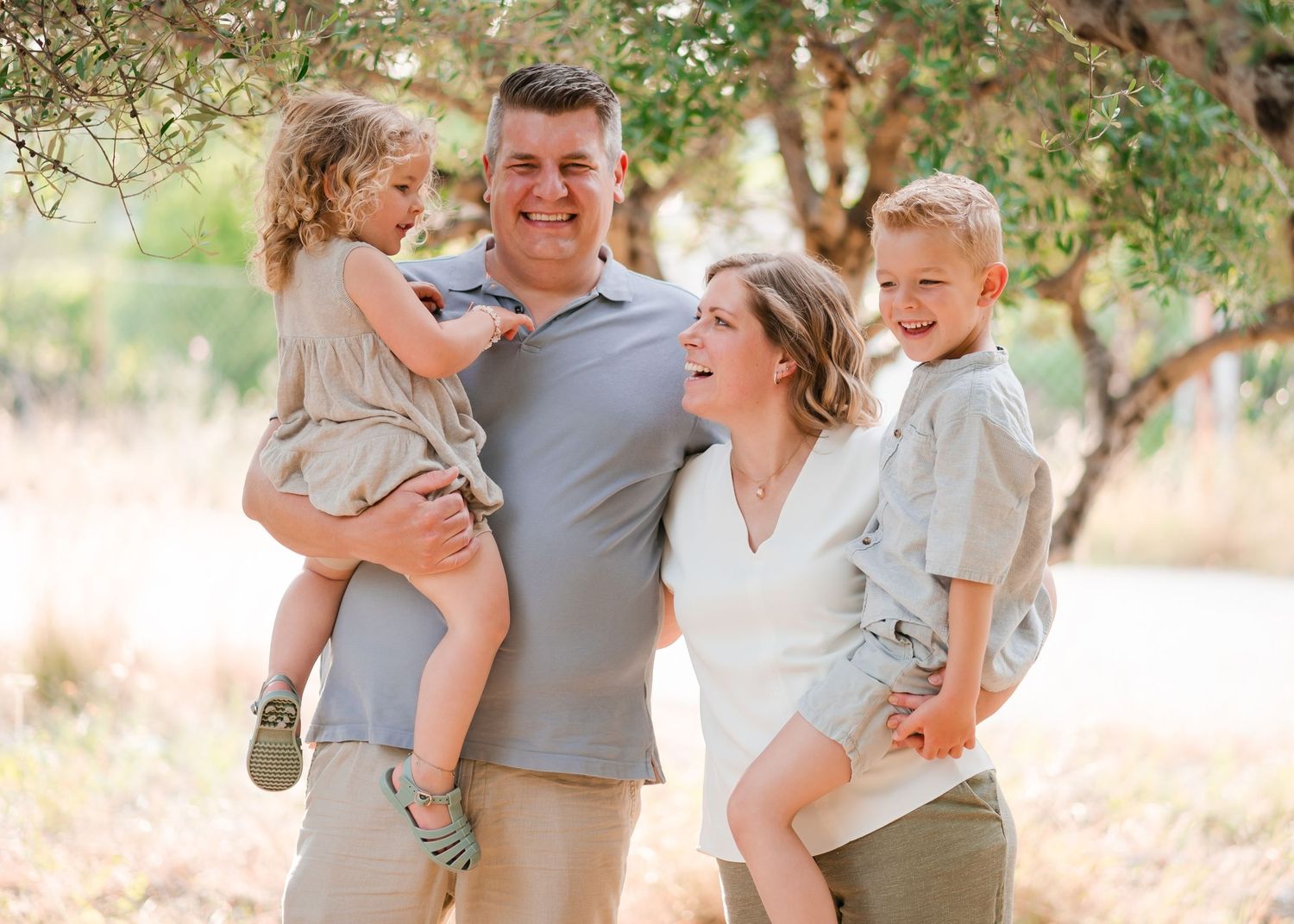 A family shar es joyful moments together under a tree in natural lighting. Fotograf Rhodos