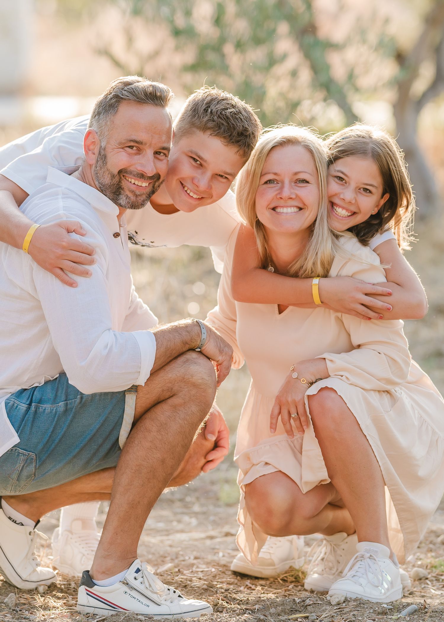 Casual outdoor portrait of group hugging and smiling in golden afternoon light. Fotograf Rhodos