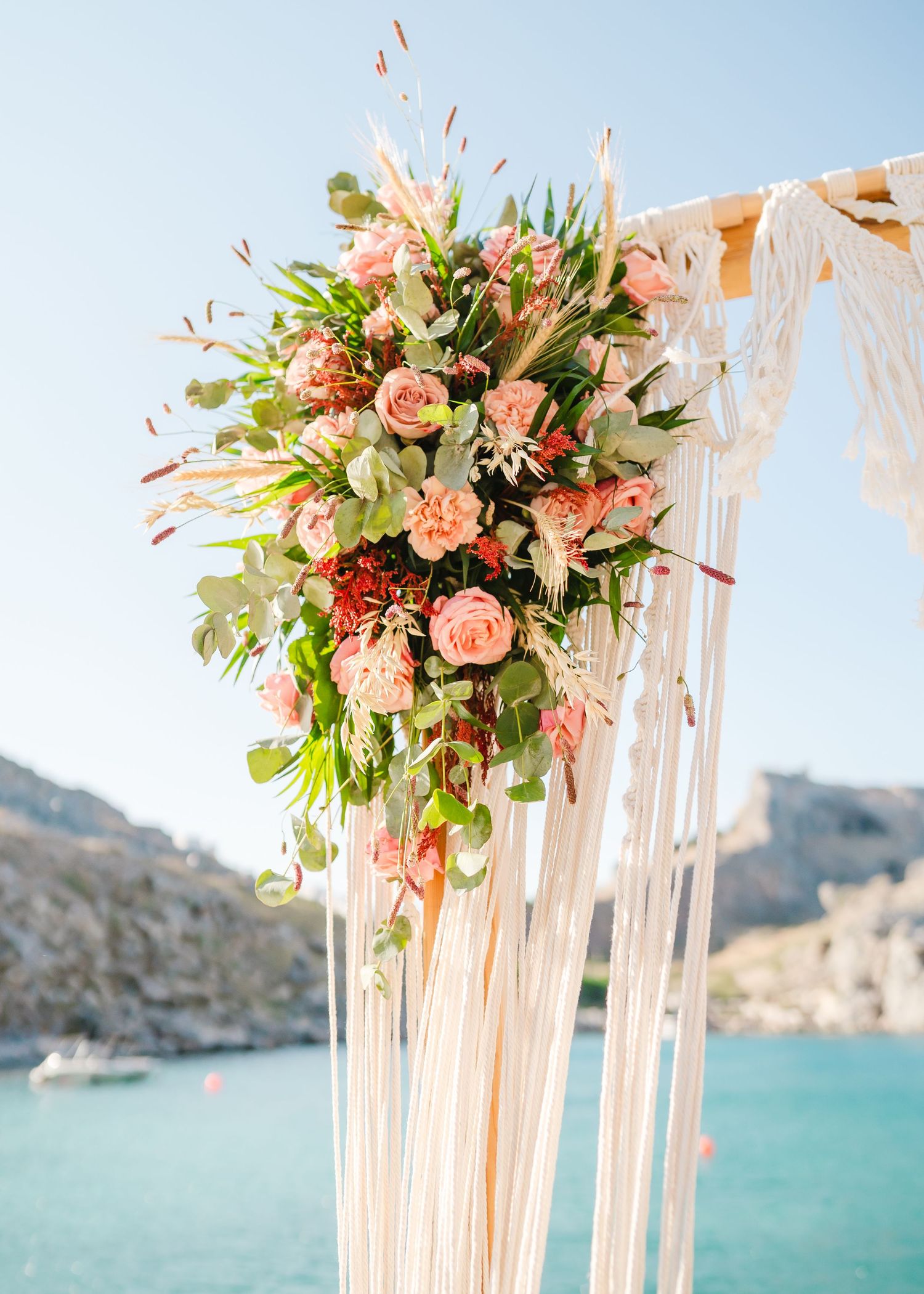 Floral wedding arch arrangement with pink roses and greenery against blue ocean bacHochzeit Rhodos - Hochzeitsfotograf Rhodos Tina Luckdrop.