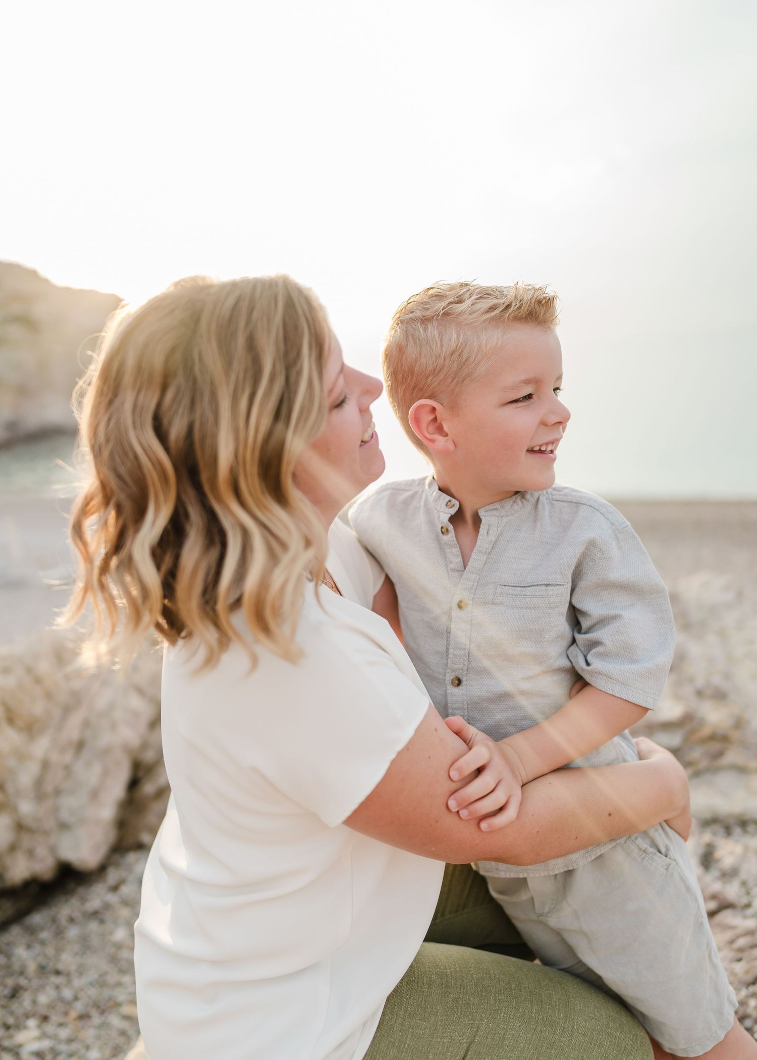Parent and child share a playful moment on rocky coastal terrain. Fotograf Rhodos