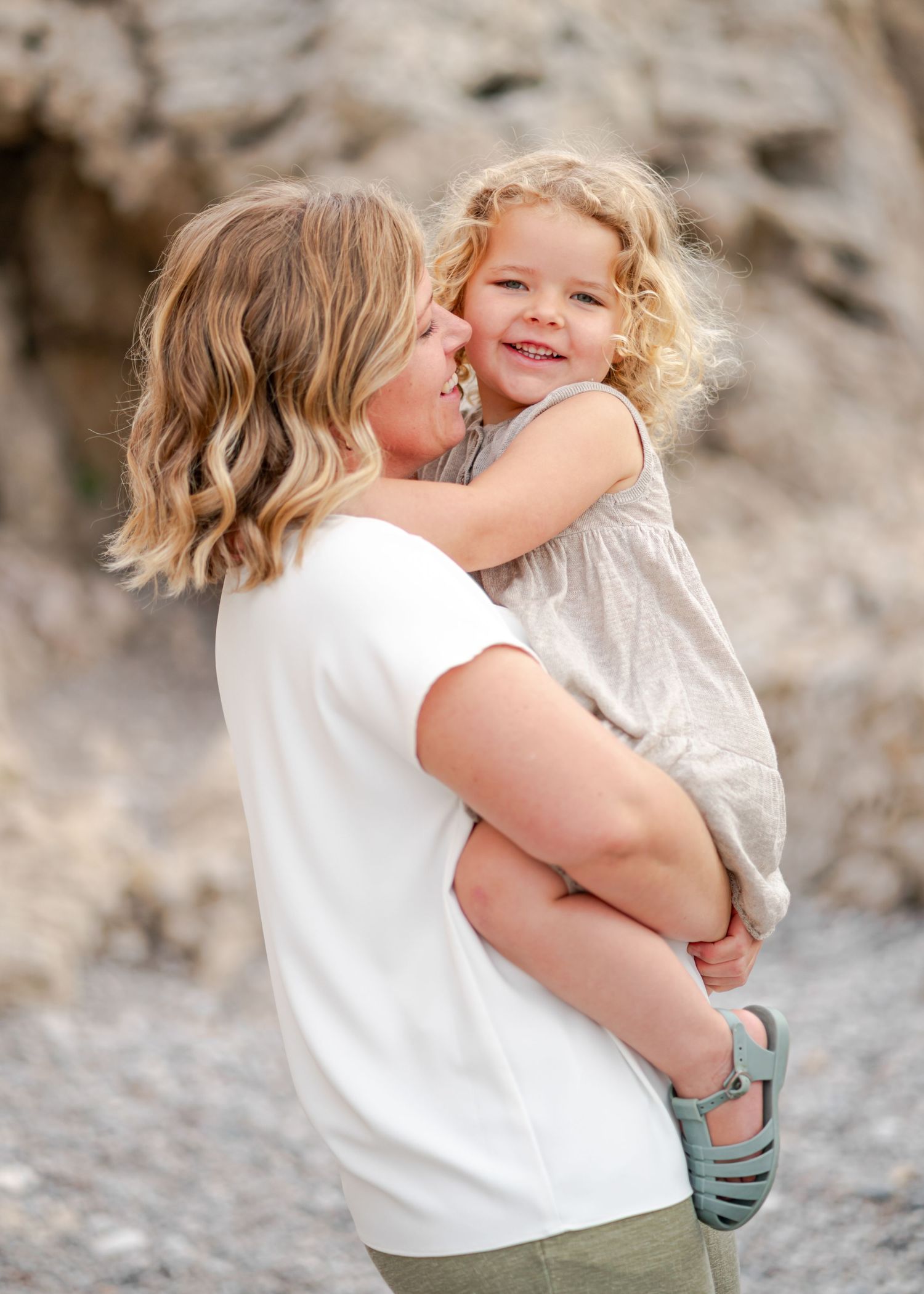 Sweet candid moments between parent and child sharing hugs on rocky beach. Fotograf Rhodos