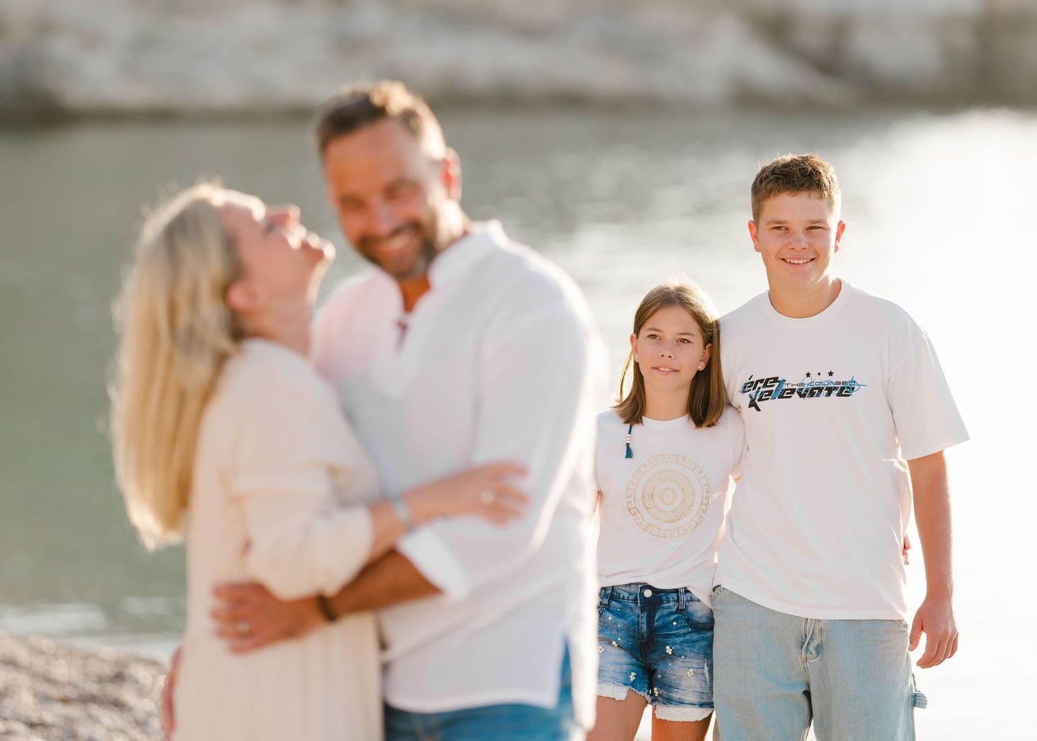 A candid family moment on a rocky beach with cliffs and water in the background. Fotograf Rhodos