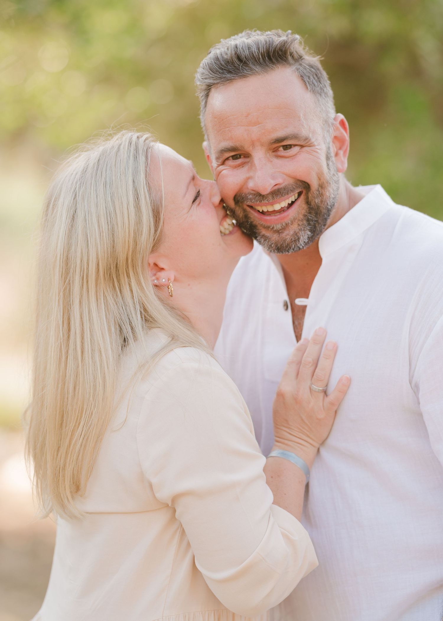 A couple sharing a tender moment outdoors in white clothing during sunset. Fotograf Rhodos