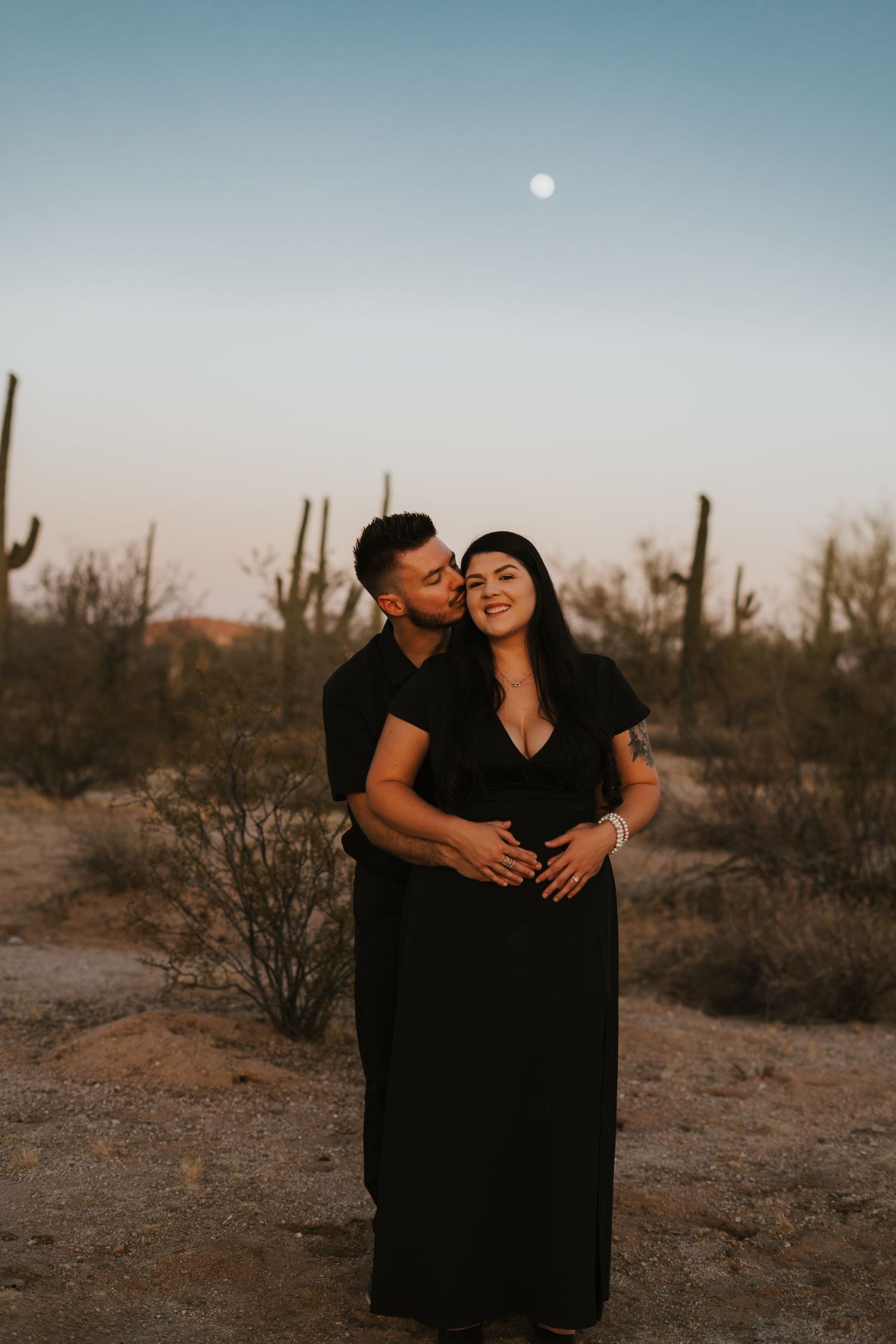 Couple embracing blue hour in the Arizona desert under a full moon. Captured with warmth and romantic tones.
