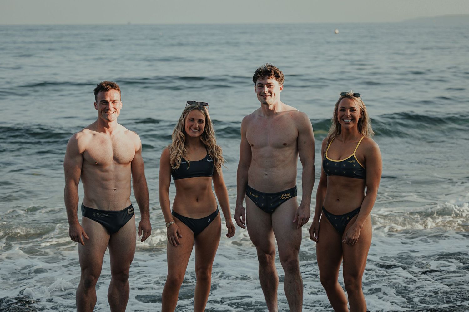 Two couples enjoying beach day together in swimming attire.