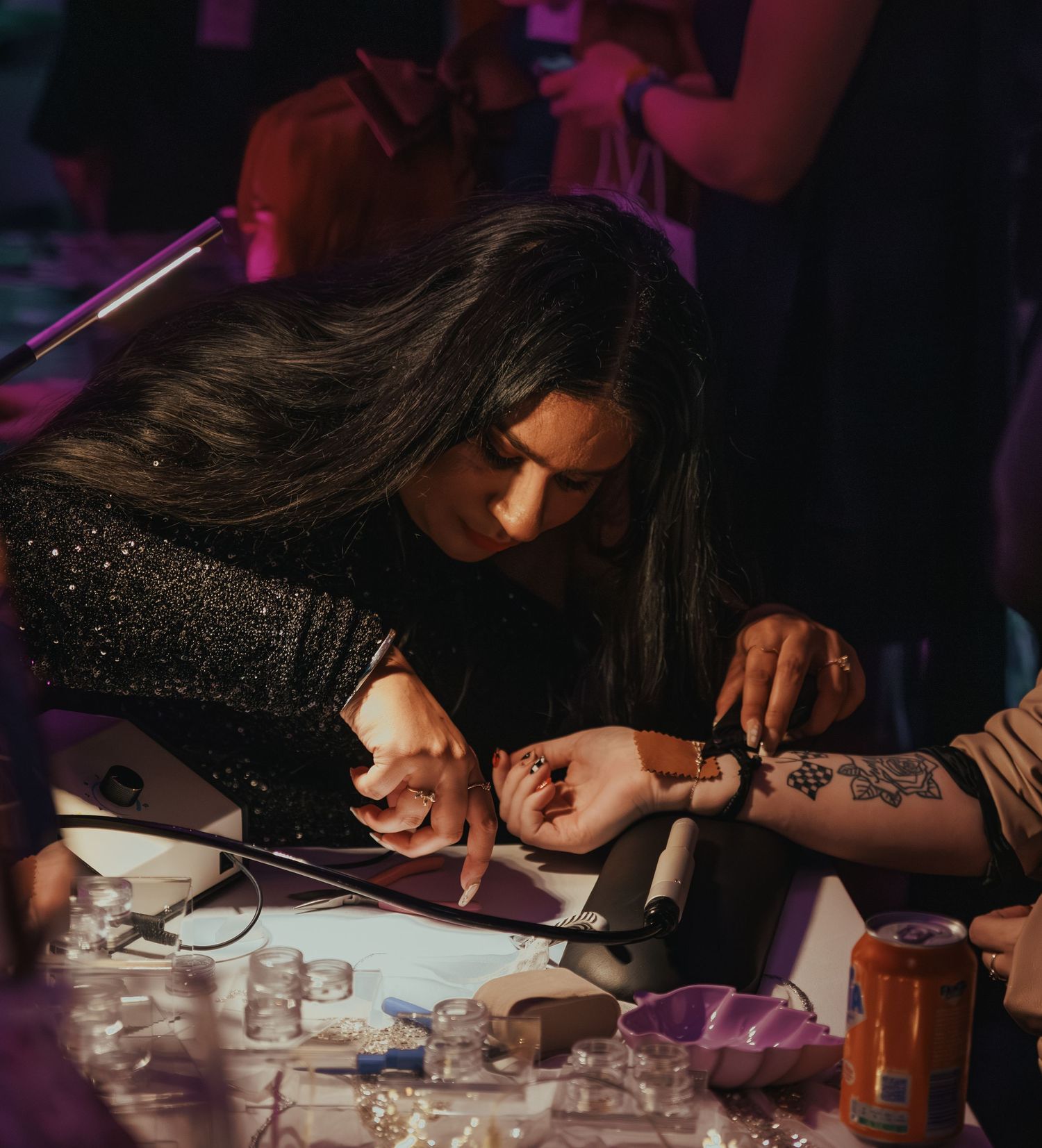 Artist drawing intricate tattoo design in dimly lit room with purple lighting.