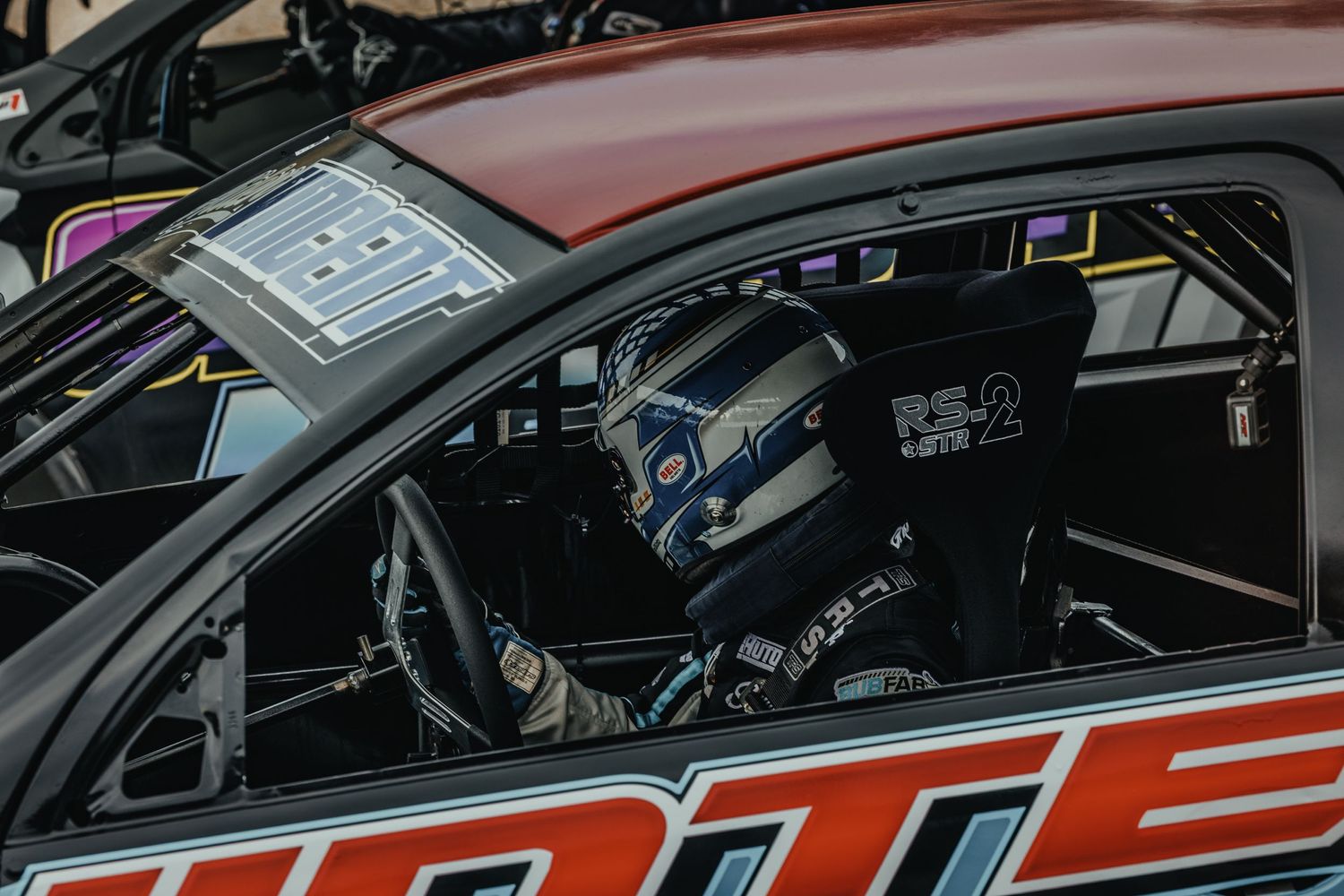 Interior view of a race car showing racing seat, roll cage and safety equipment.