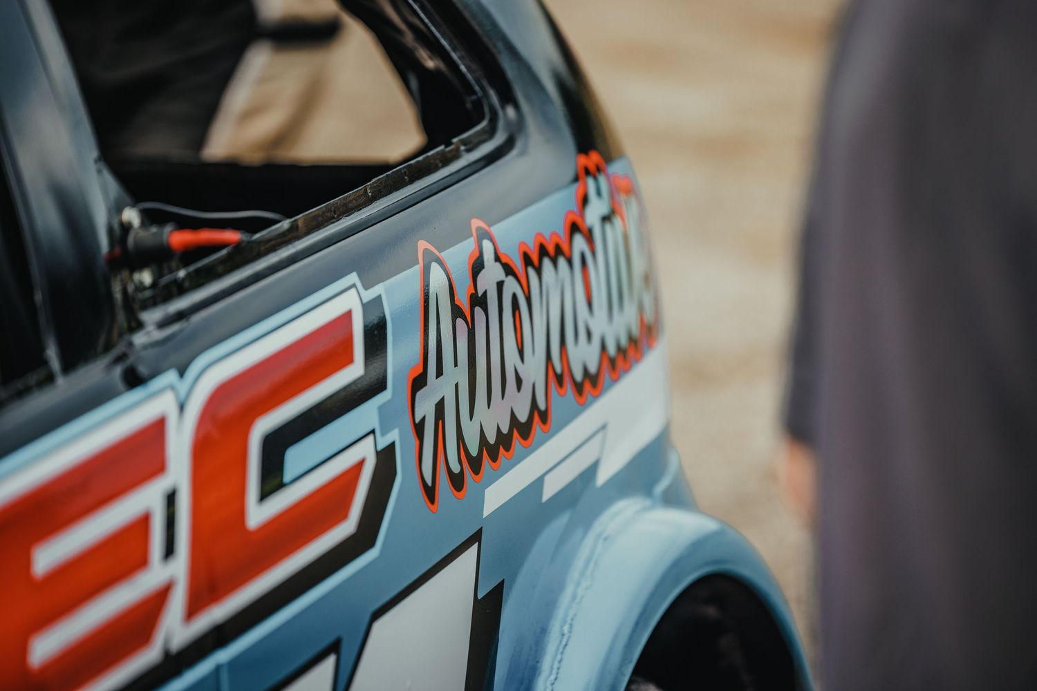Detail shot of race car decal showing red text graphics on vehicle door.