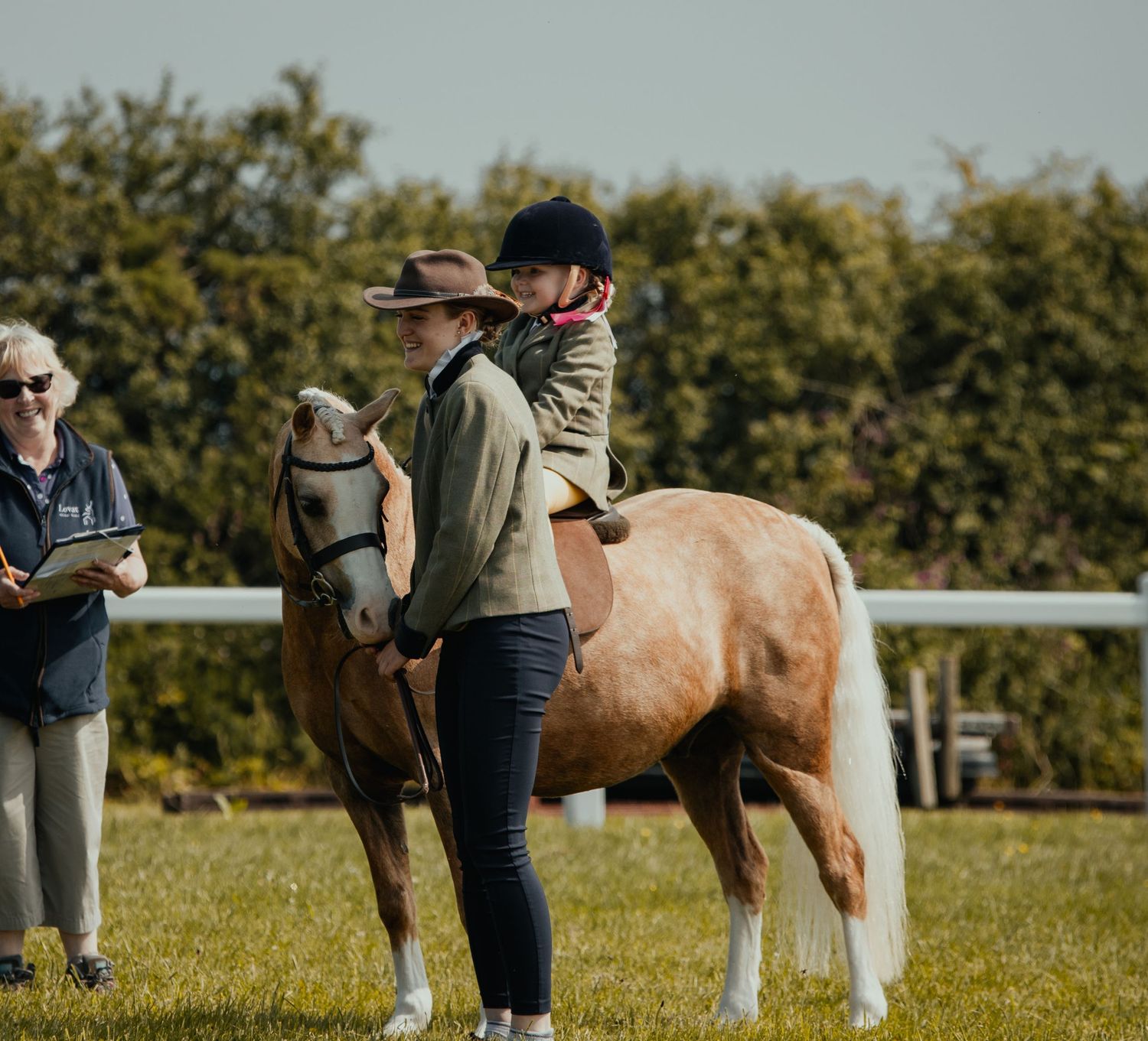 People gathered around a palomino horse at an equestrian event.