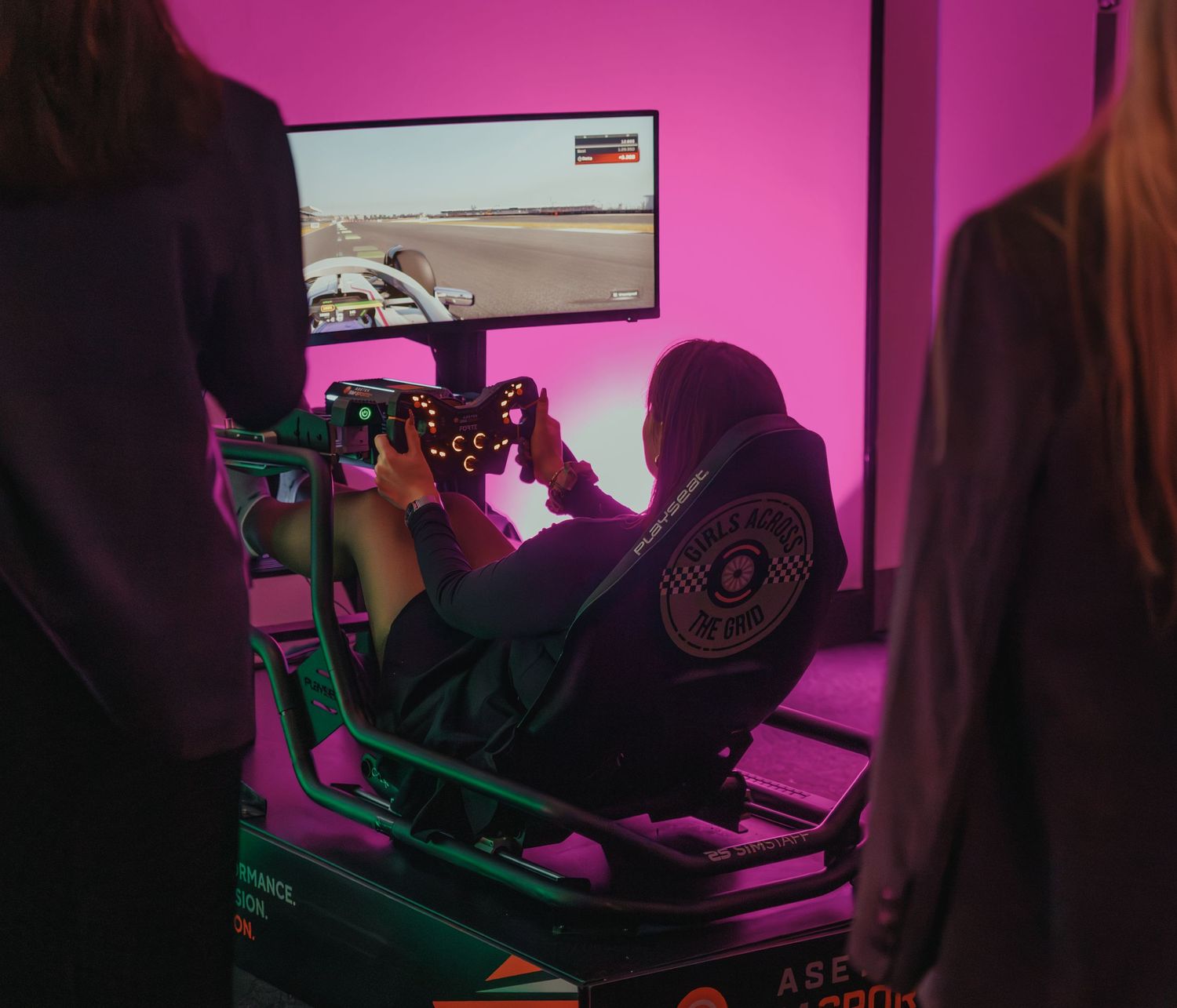 Person using racing simulator setup with pink ambient lighting.