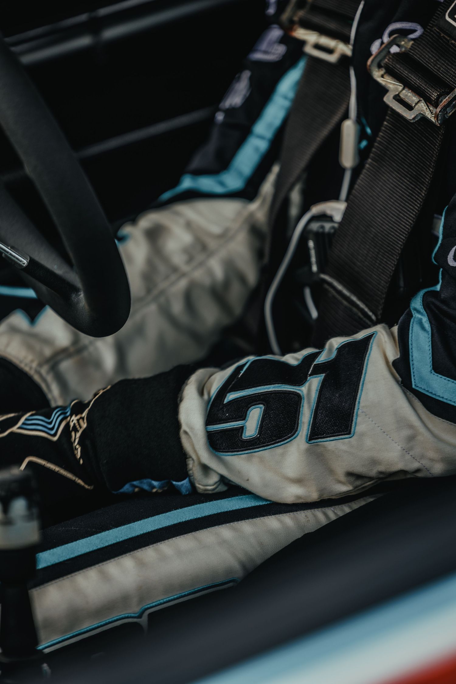 Close-up detail of racing seat and safety harness inside competition vehicle.