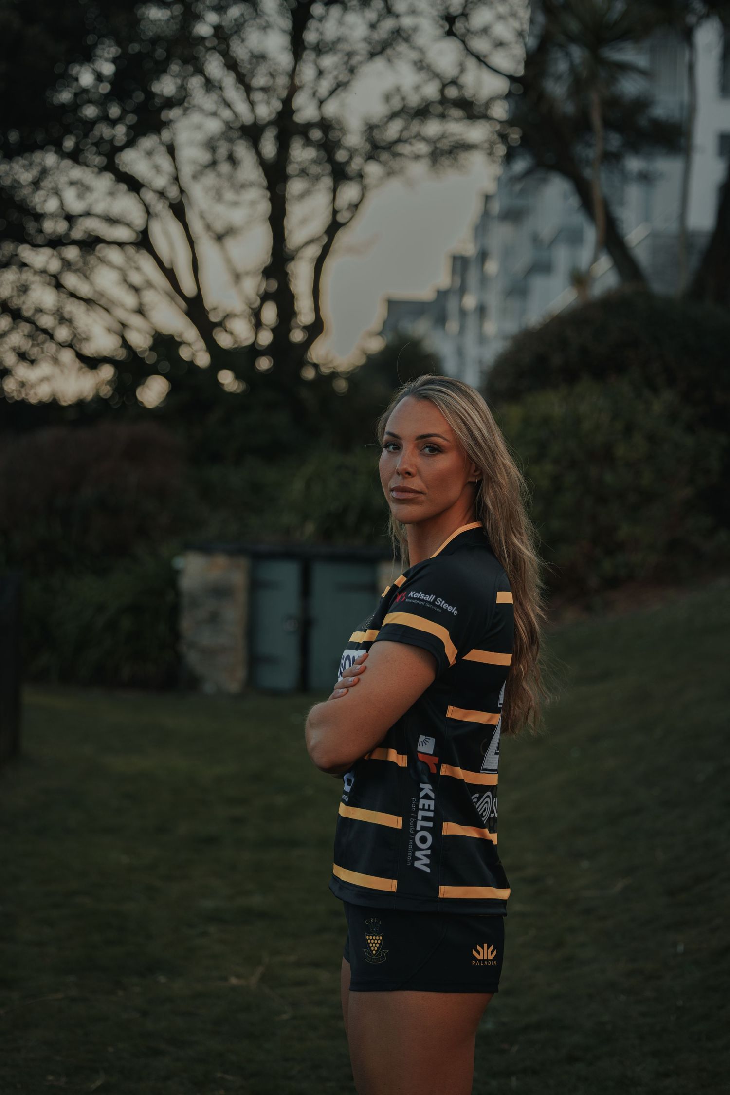 Person in striped rugby uniform poses against dusky evening sky.