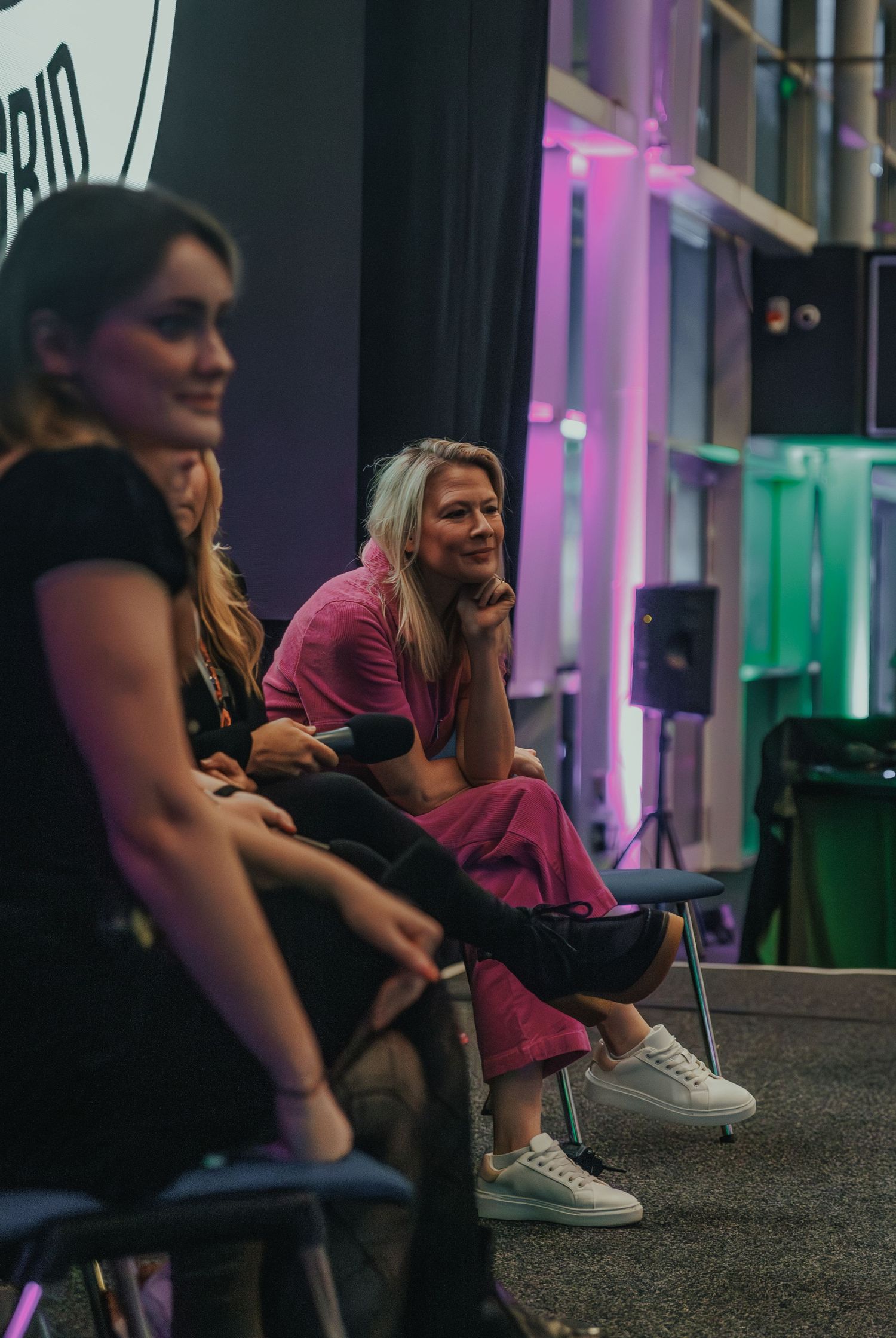 People relaxing in casual attire at an indoor venue with colorful lighting.