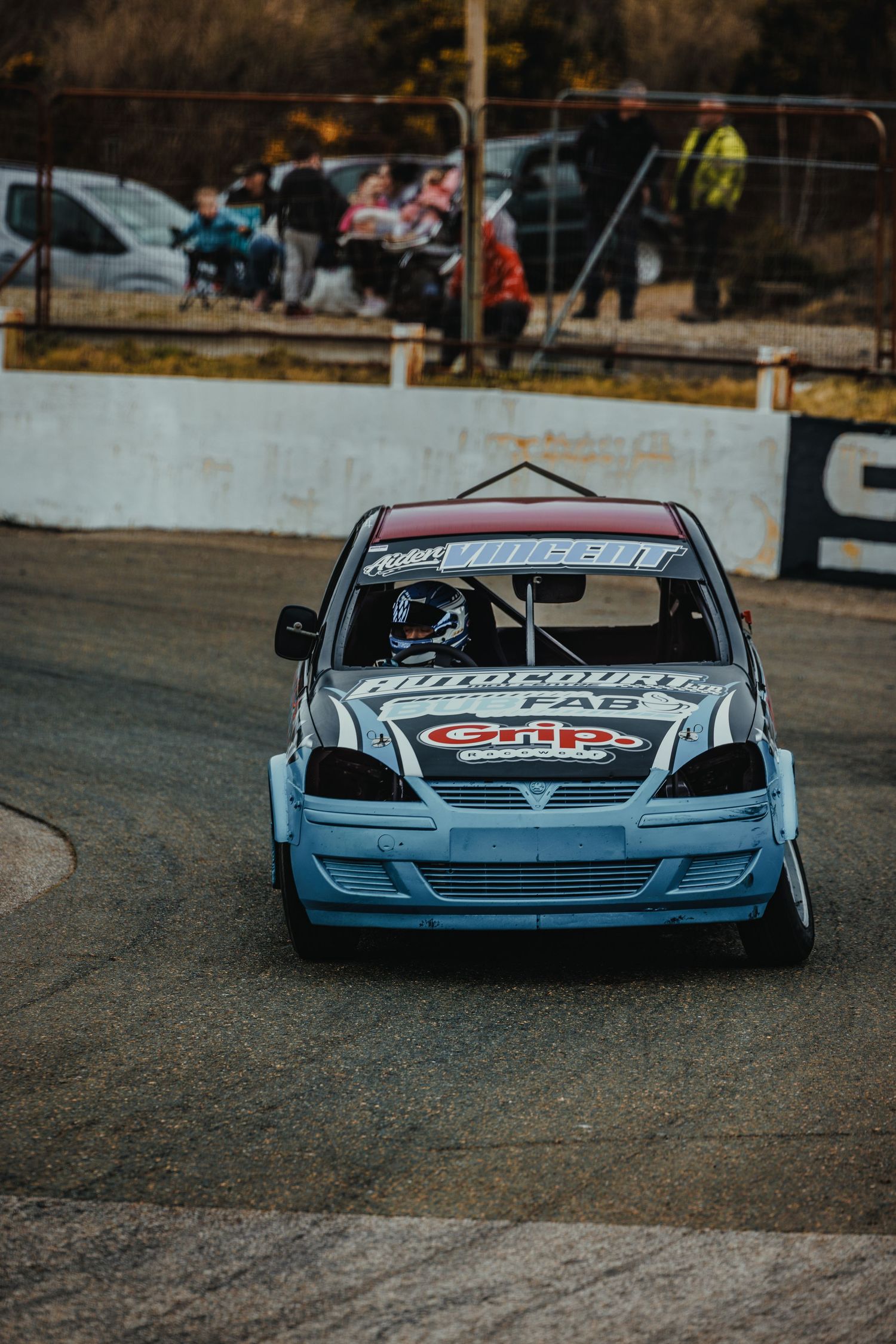 Light blue stock car navigates a turn on the racing circuit.
