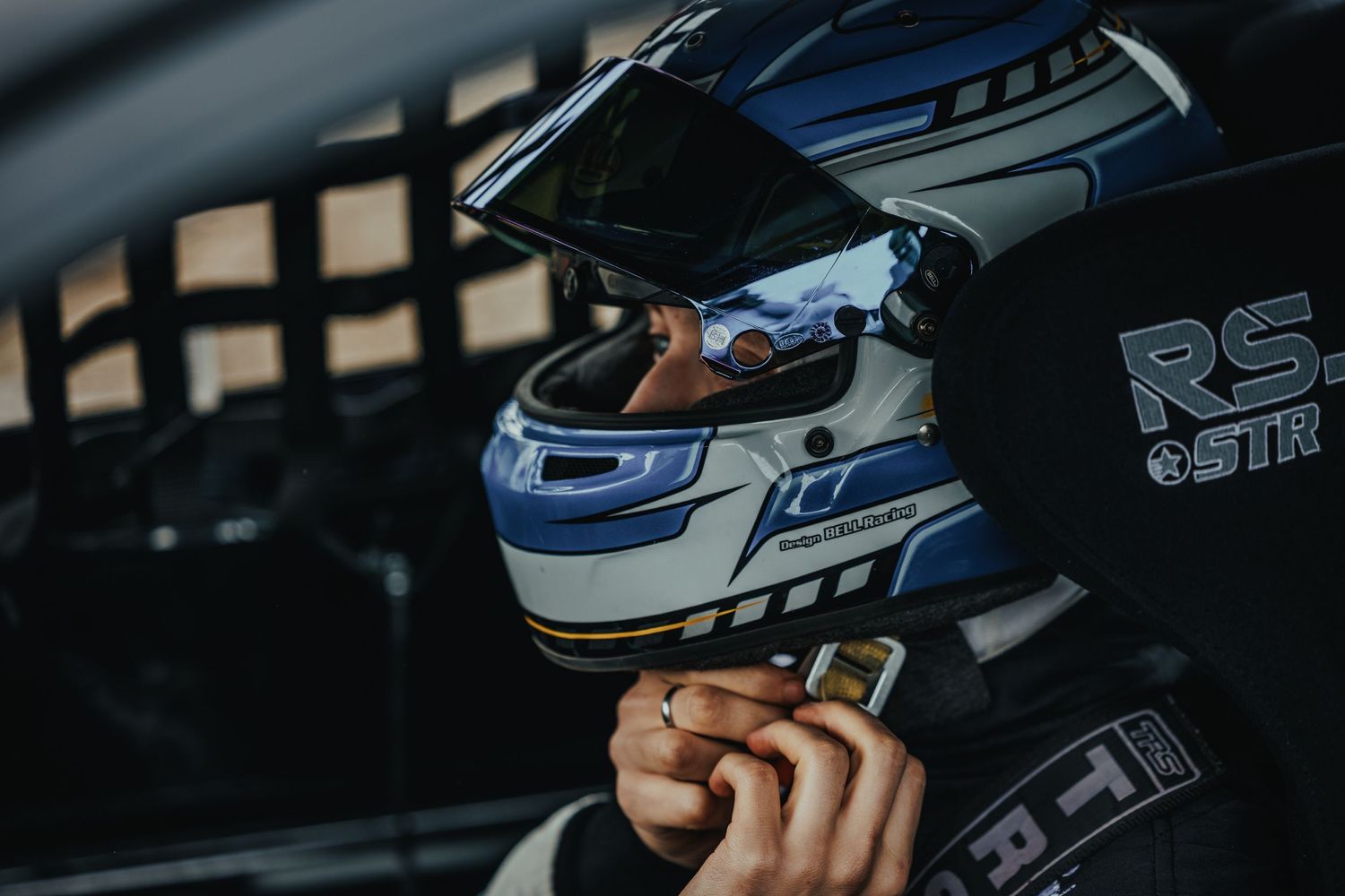 Racing helmet with visor photographed through protective window netting.