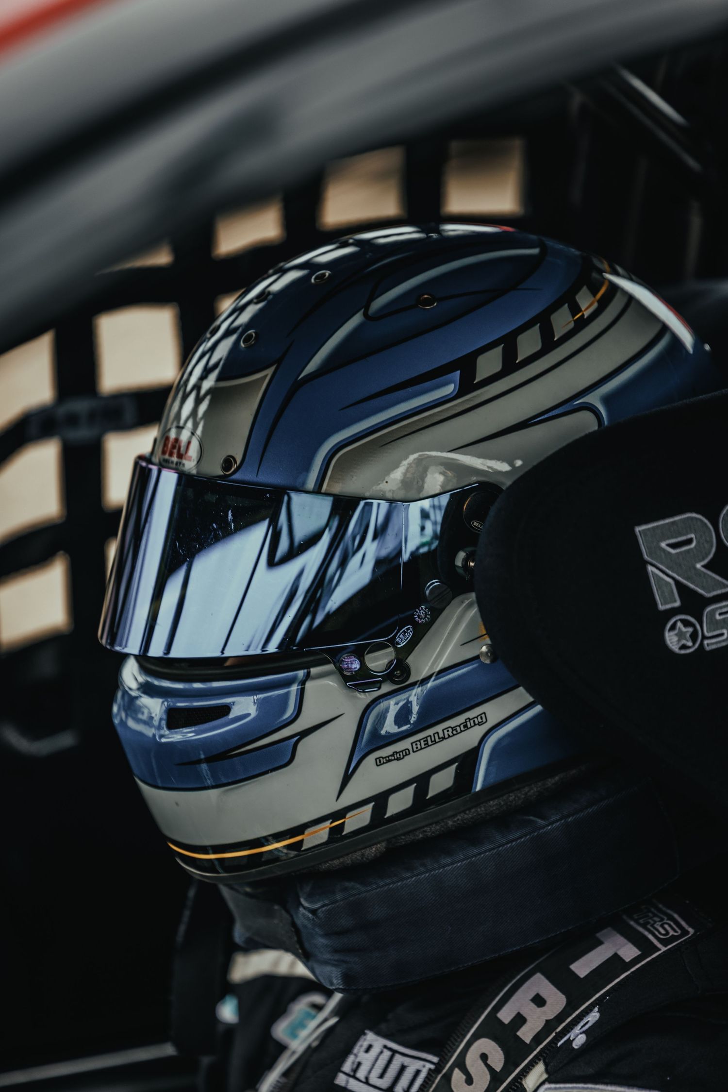 Close-up of a white and blue racing helmet with reflective visor inside a race car.