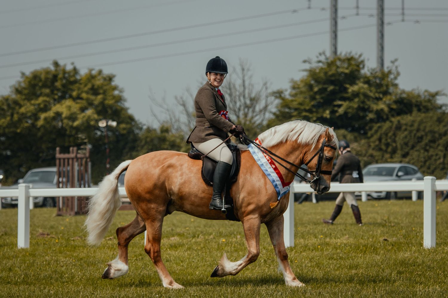 A rider aboard a chestnut and white draft horse in an outdoor arena.