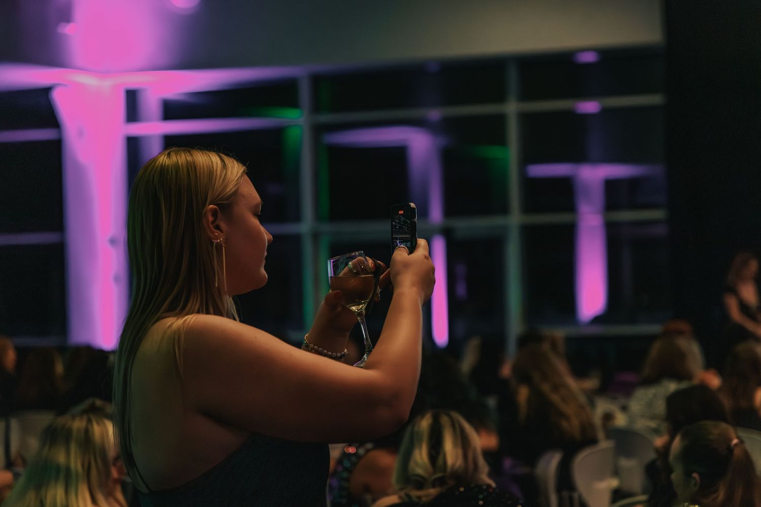 Person holding microphone in dimly lit venue with purple lighting.