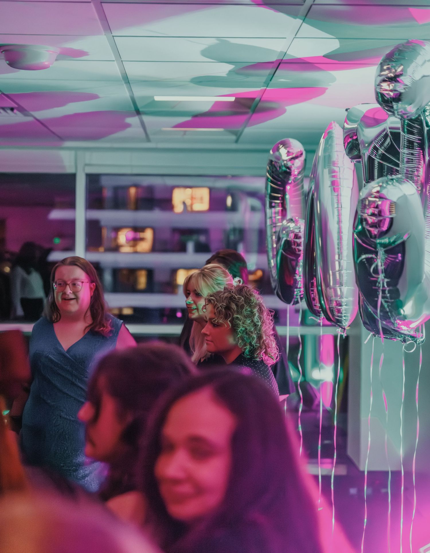 Party scene with balloons and pink lighting creating vibrant atmosphere.