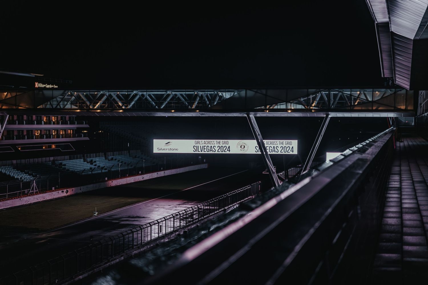 Dark nighttime view of empty stadium bleachers and structural framework.