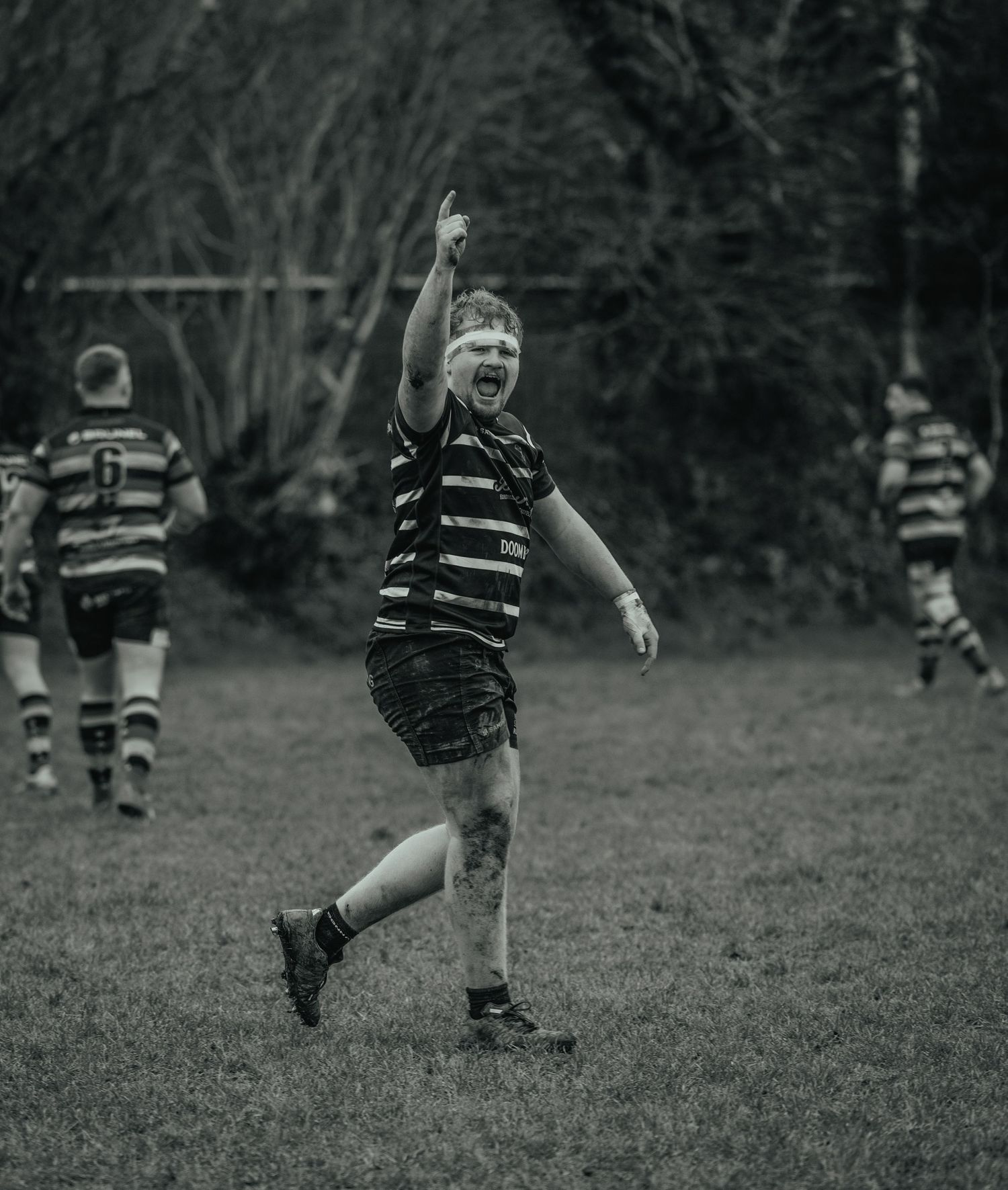Rugby player celebrates with raised arm during match in black and white photograph.