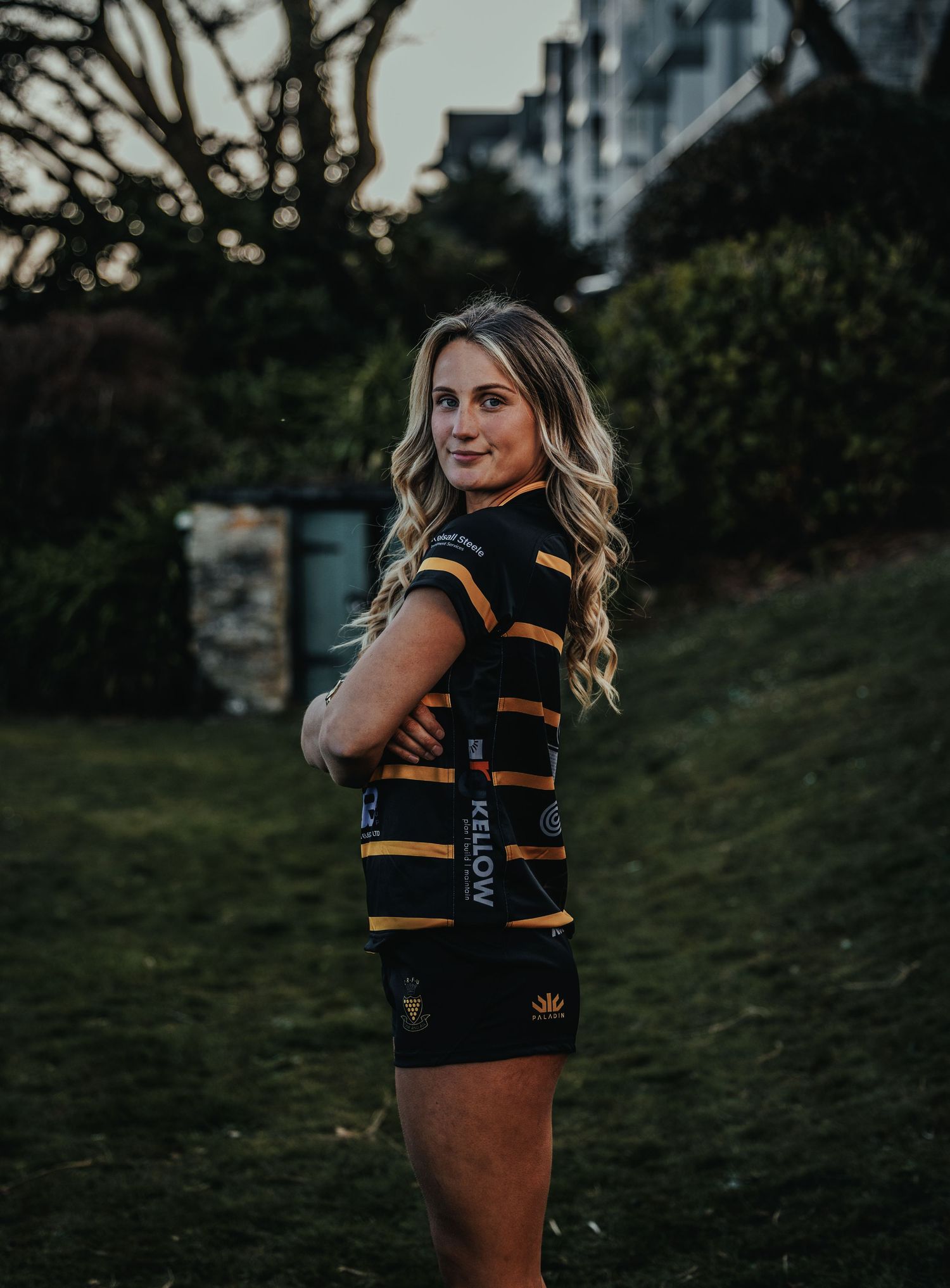 Person wearing black and yellow striped athletic uniform poses outdoors at dusk.