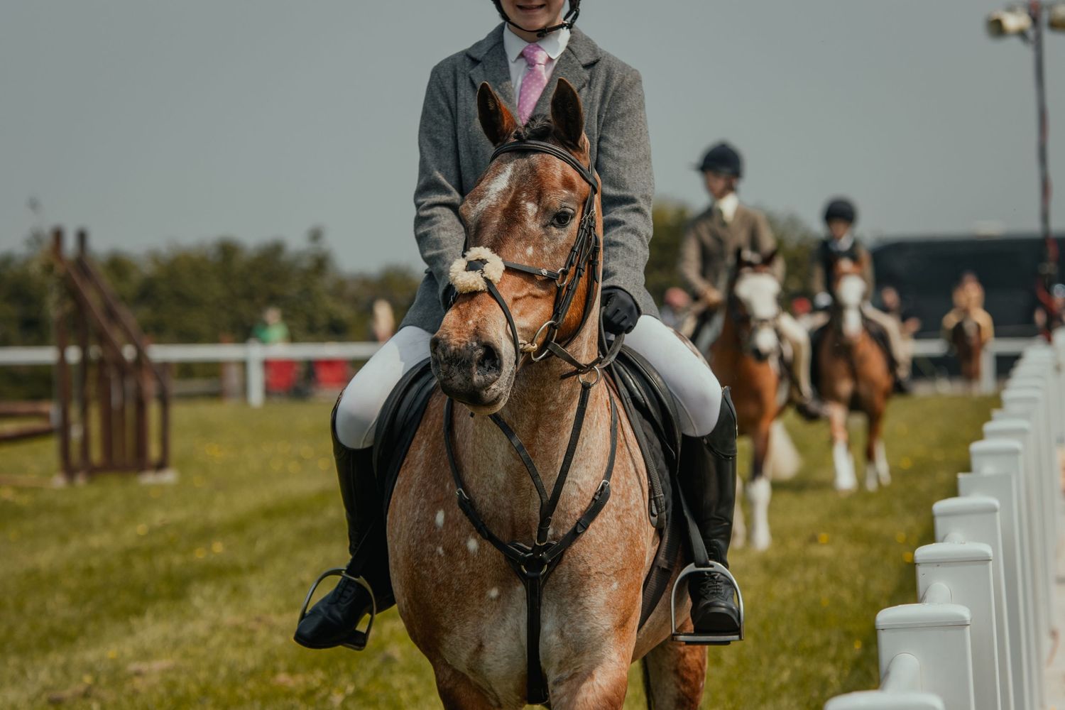 Equestrian riders in formation during horse show with white fencing along the arena.