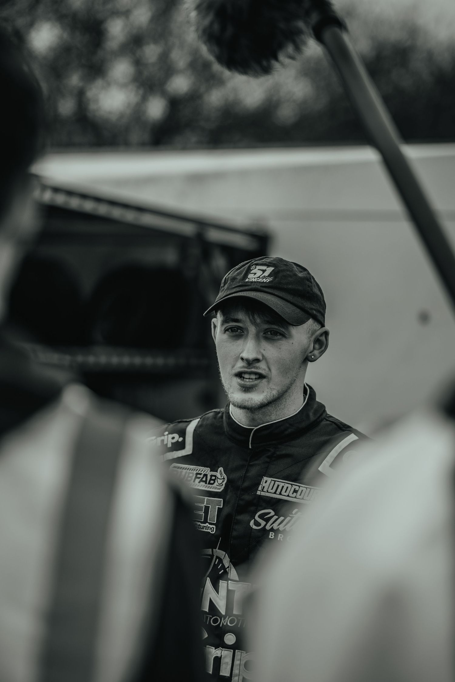 Black and white portrait of racing driver in team uniform.