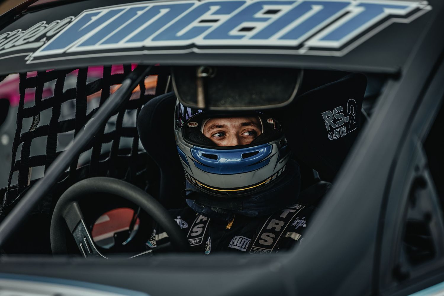 Racing helmet visible through car window during motorsport competition.