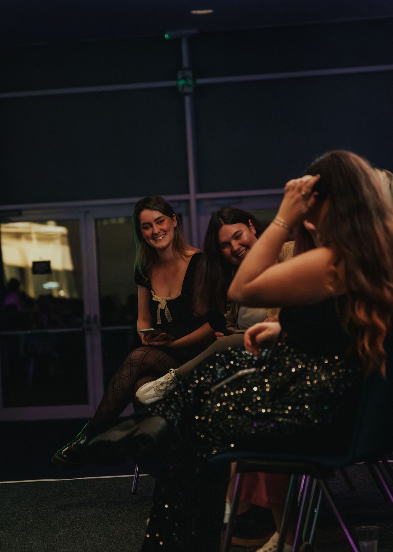 Friends laughing together during an evening event with sparkly dresses.