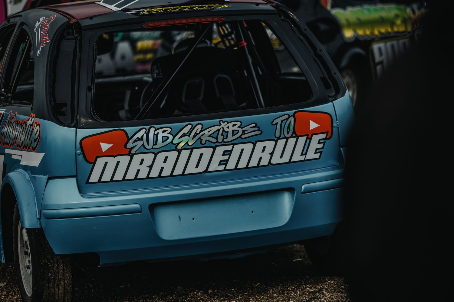 Close-up of blue race car displaying Manderule branding and sponsorship decals.